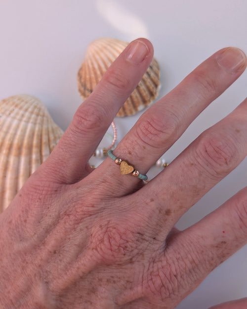 Bague elastique coeur diamanté et perles gold filmer. Portée au doigt dune Femme. 
Créations artisanales La Tête dans les Nétoiles 