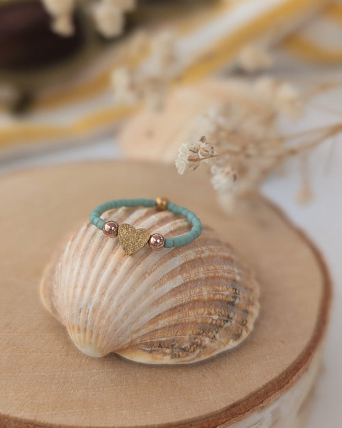 Bague élastique coeur diamanté et gold filled rose posé sur coquillage . 
Créations artisanales La Tête dans les Nétoiles 