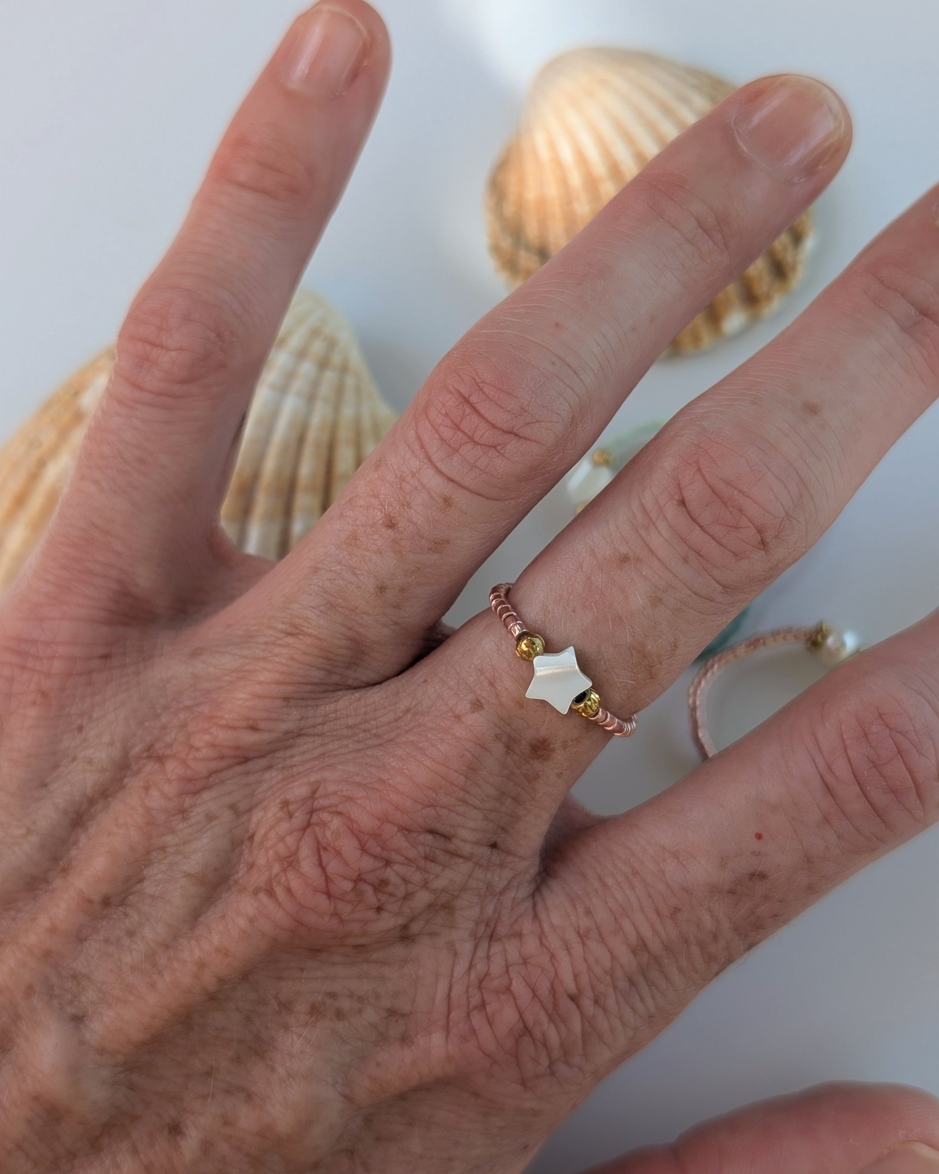 Bague élastique mini etoile nacre portée par une femme. Perles miyuki. Créations artisanales La Tête dans les Nétoiles 