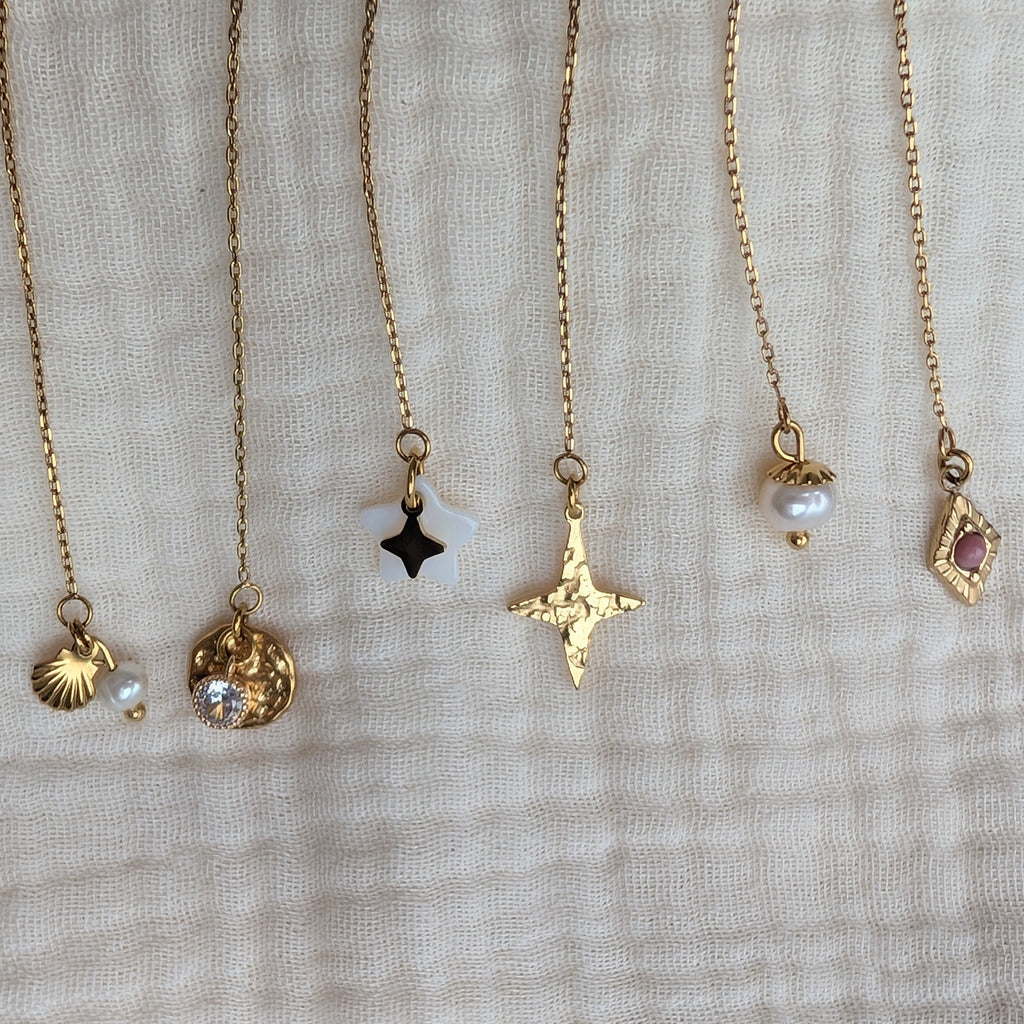 Bar à boucles zoom sur les chainettes d'oreilles et les grigri. coquillages perle de nacre etoile des vents losange martelé. Créations La tête dans les Nétoiles