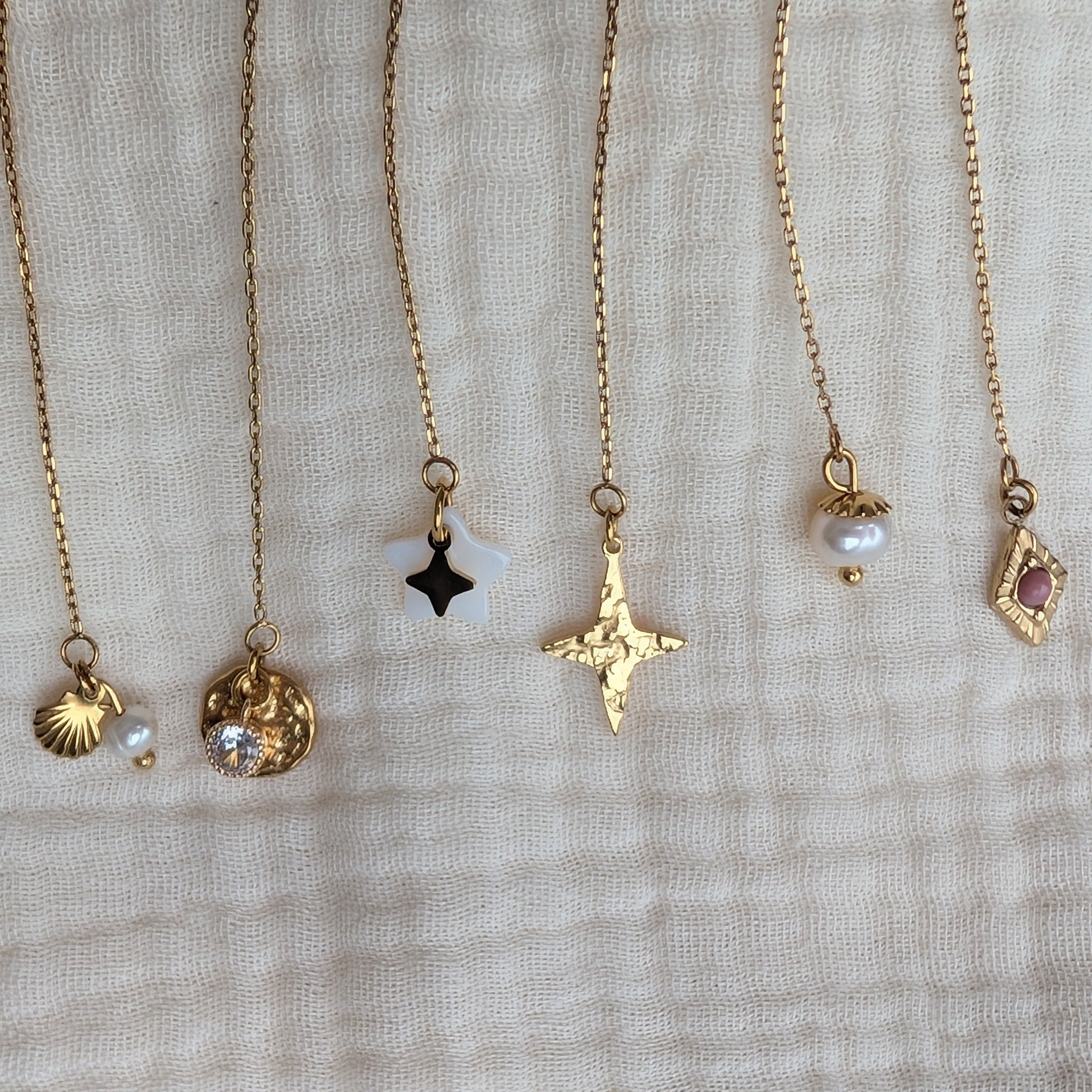 Bar à boucles zoom sur les chainettes d'oreilles et les grigri. coquillages perle de nacre etoile des vents losange martelé. Créations La tête dans les Nétoiles