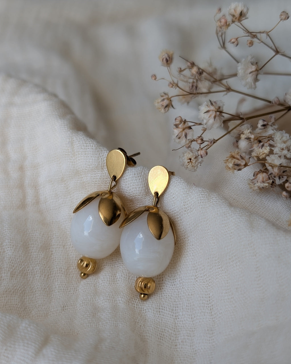 Boucles d'oreilles Olivia colori blanc nacré et acier inoxydable doré. Posées sur gaze de coton. Créations arttisanales La Tête dans les Nétoiles