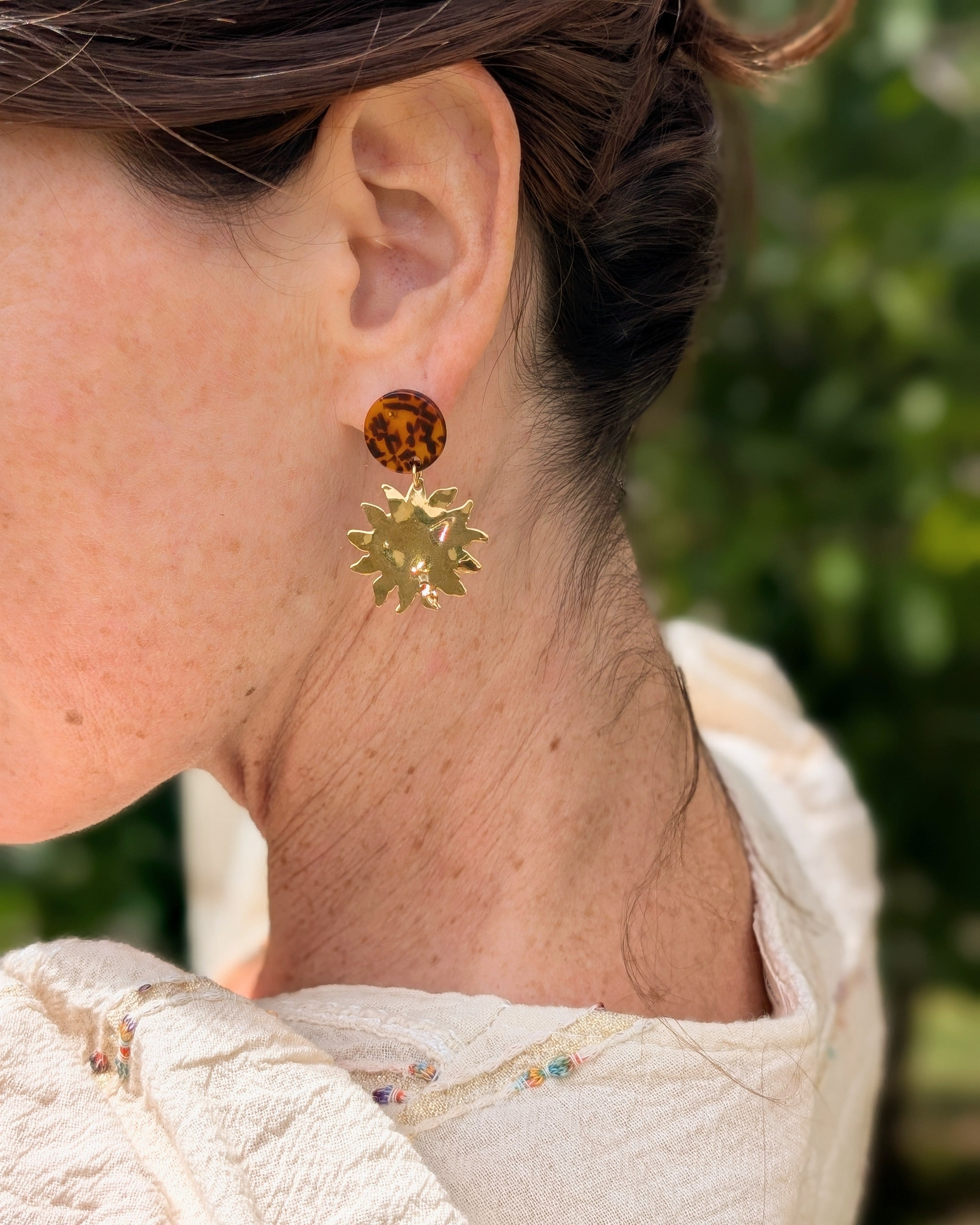 boucles d'oreilles Soline acétate terrazzo et pendentif soleil. Portées par une femme. Création La Tête dans les Nétoiles. 