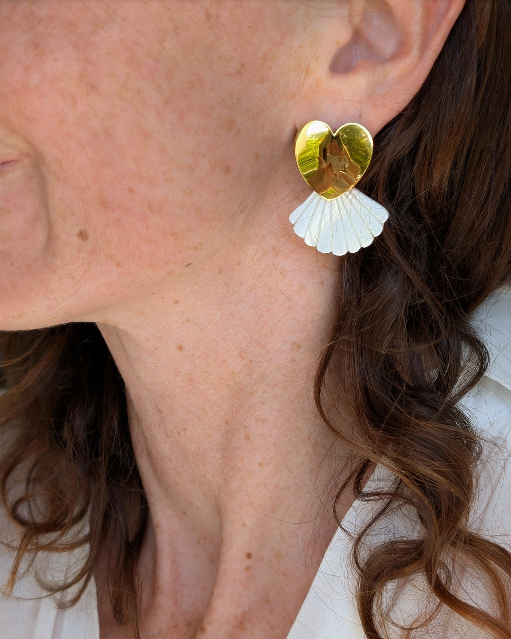 boucles d'oreilles coeur en acier inoxaydable doré et éventail nacre Amélia portées par une femme. Créations artisanales La Tête dans les Nétoiles