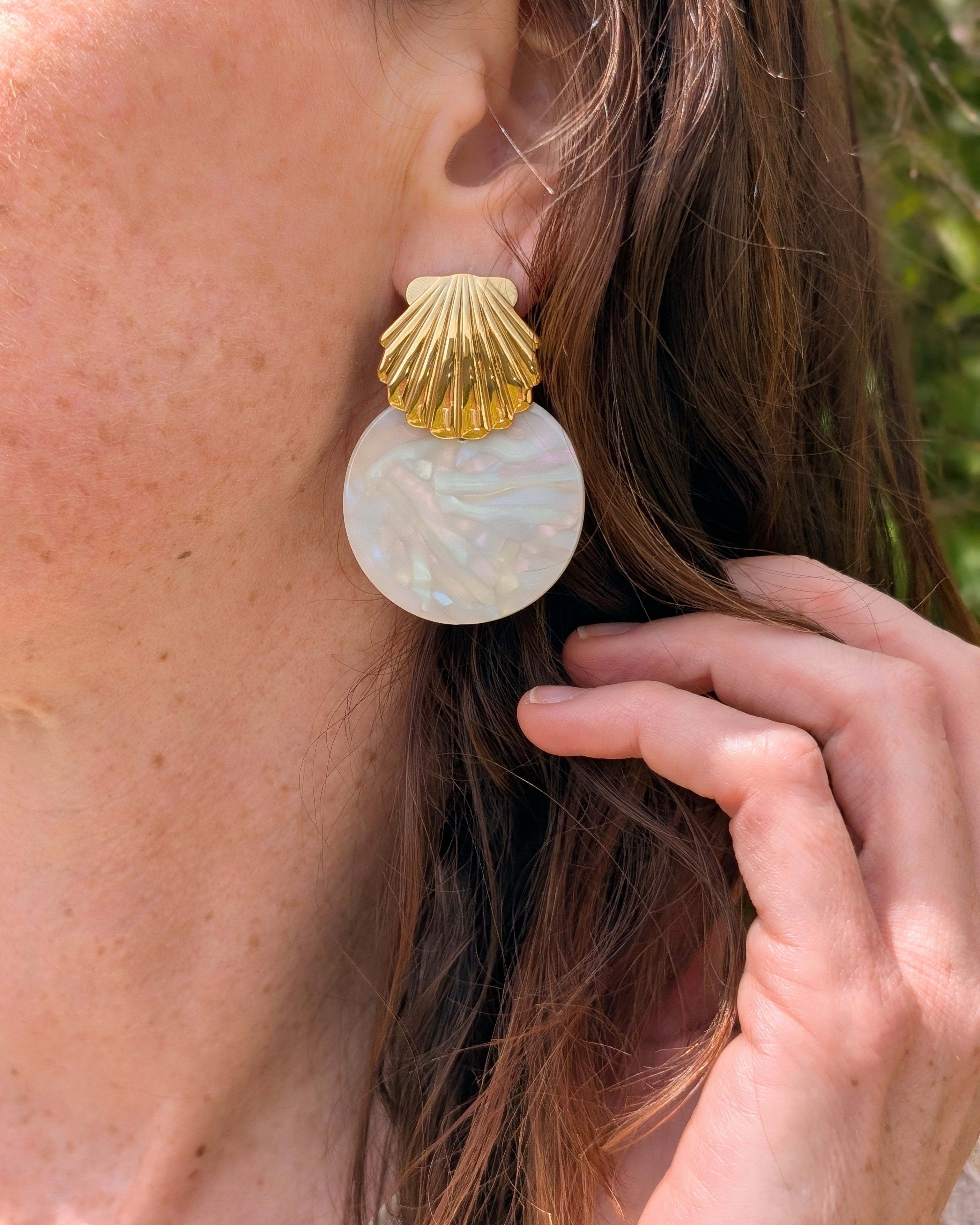 Boucles d'oreilles Calypso coquillage et acétate irisé. Porté par une femme vue en gros plan. Création La Tête dans les Nétoiles