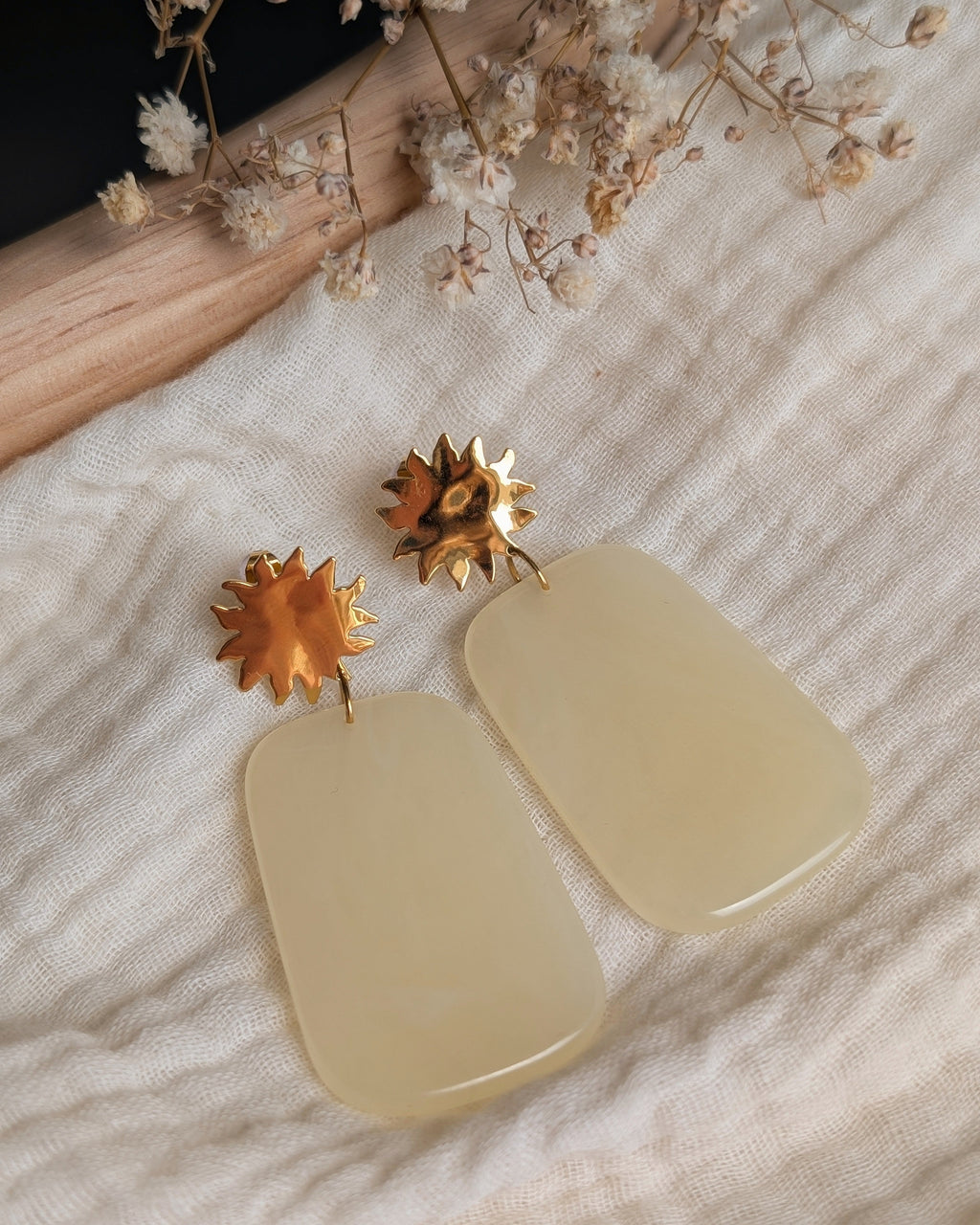 Boucles d'oreilles résine jaune pastel et soleil acier inoxydable Alba. Posées sur gaze de coton. Créations artisanales La Tête dans les Nétoiles 
