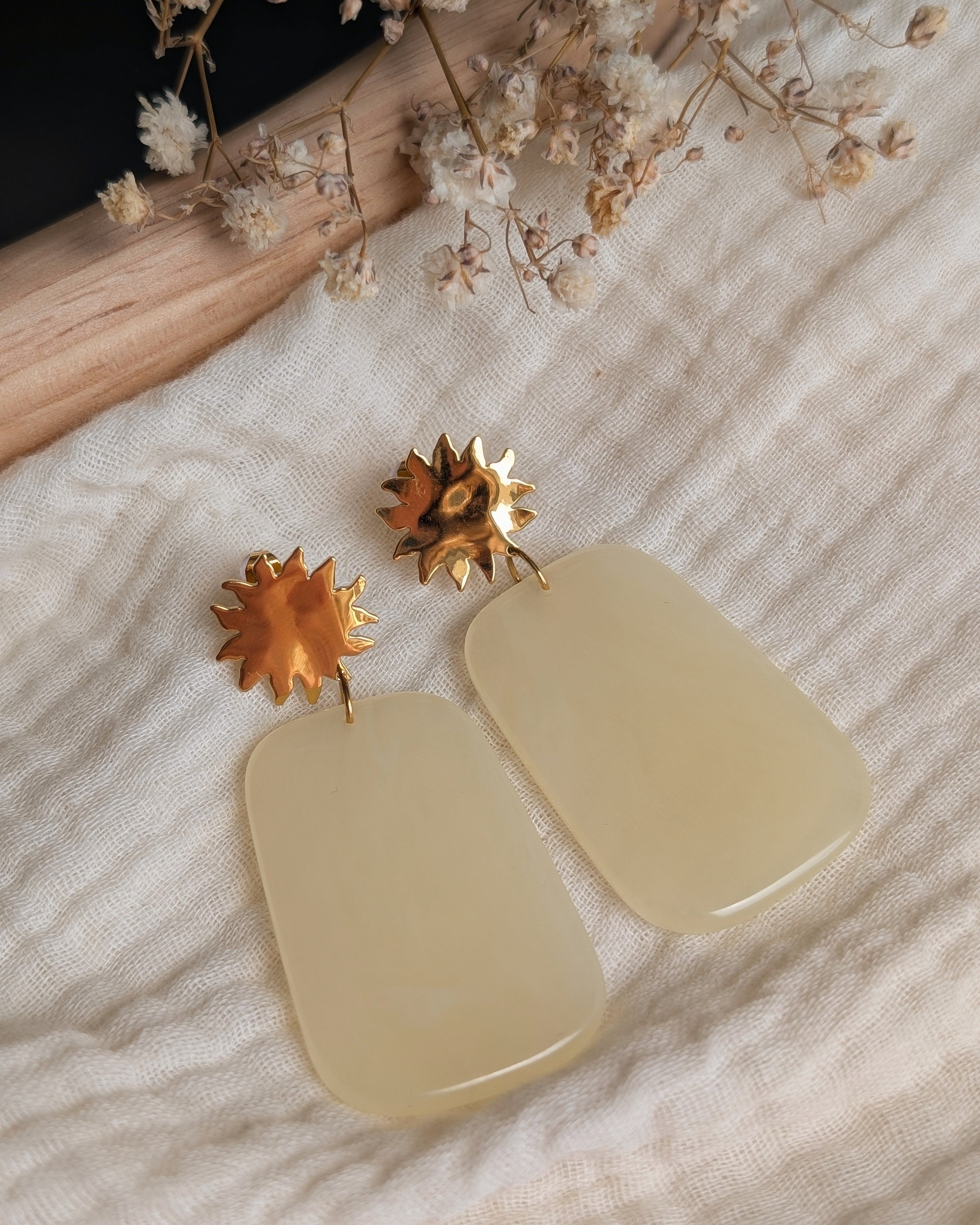 Boucles d'oreilles résine jaune pastel et soleil acier inoxydable Alba. Posées sur gaze de coton. Créations artisanales La Tête dans les Nétoiles 