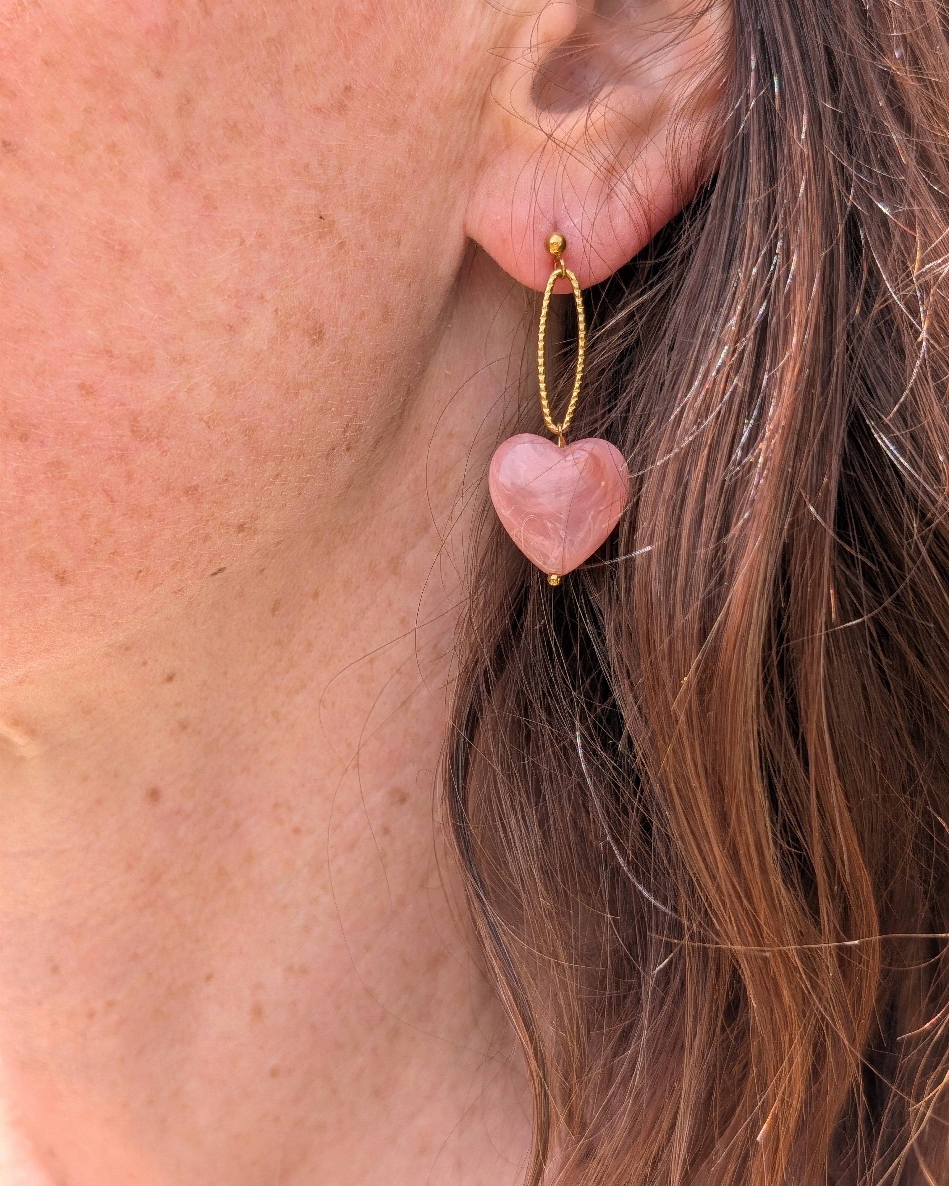Boucles pendantes Aelia coeur vieux rose marbrés portées par une femme. Création La Tête dans les Nétoiles.