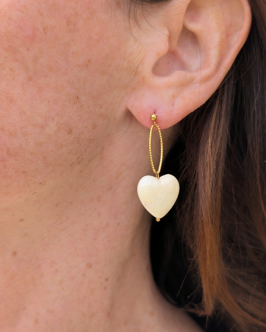 Boucles pendantes Aélia coeur écru marbré en résine. Portées par une femme. Création La Tête dans les Nétoiles