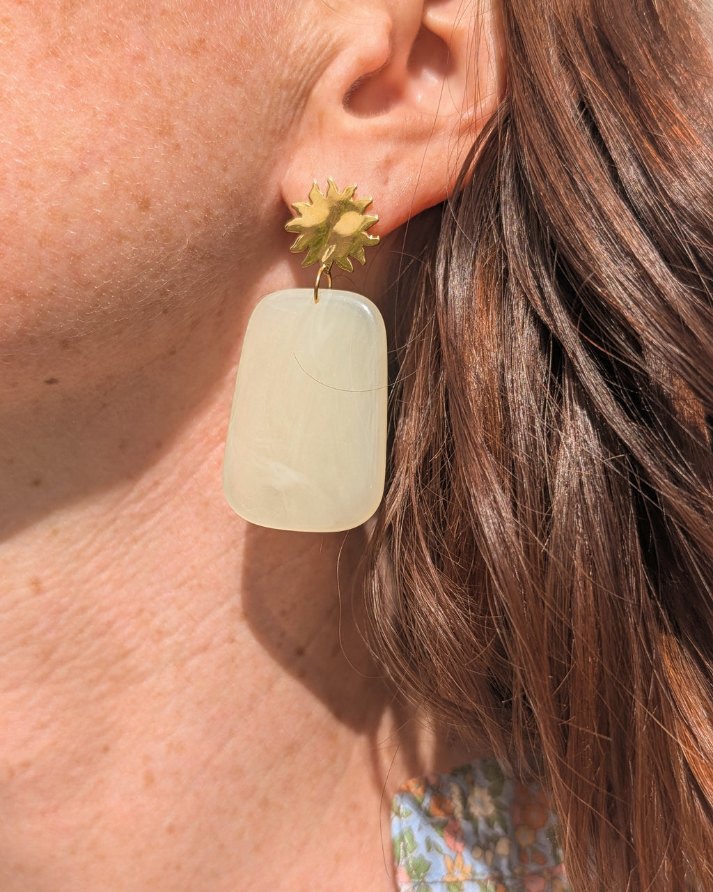 Boucles d'oreilles pendantes soleil et pendentif résine alba jaune pastel porté par une femme en gros plan. créations artisanales La Tête dans les Nétoiles 