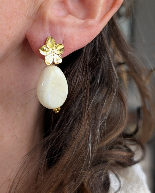 Boucles pendantes JEANNETTE fleur de cerisier acier inoxydable et perle crème en résine marbre portées par une femme création arisanale La Tête dans les Nétoiles