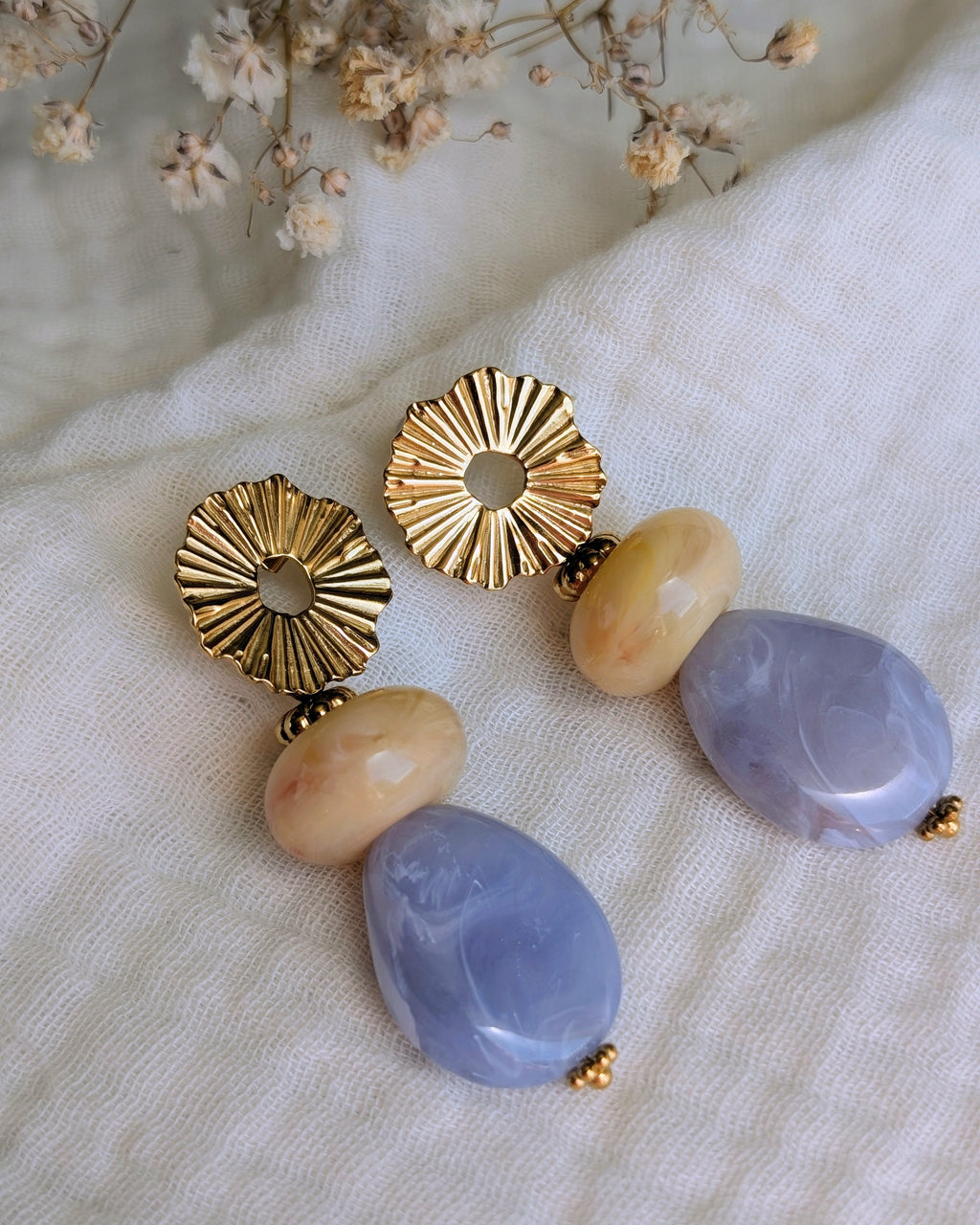 Boucles pendantes Ondine posé sur gaze de coton en version bleu. Soleil et perles en résine. Créations Artisanales la Tête dans les Nétoiles