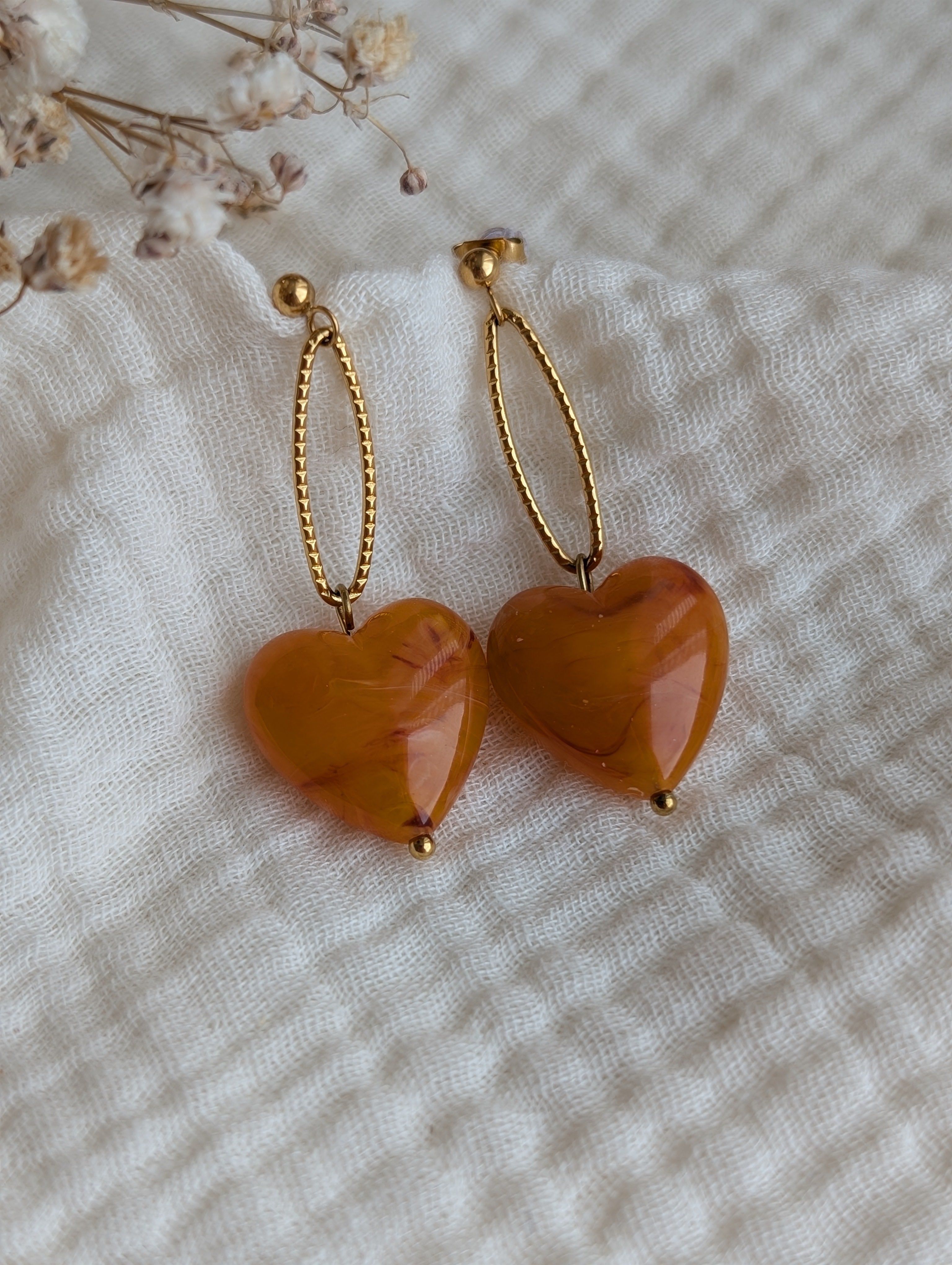Boucles pendantes Aélia coeur résine abricot posées sur gaze de coton. Création La Tête dans les nétoiles