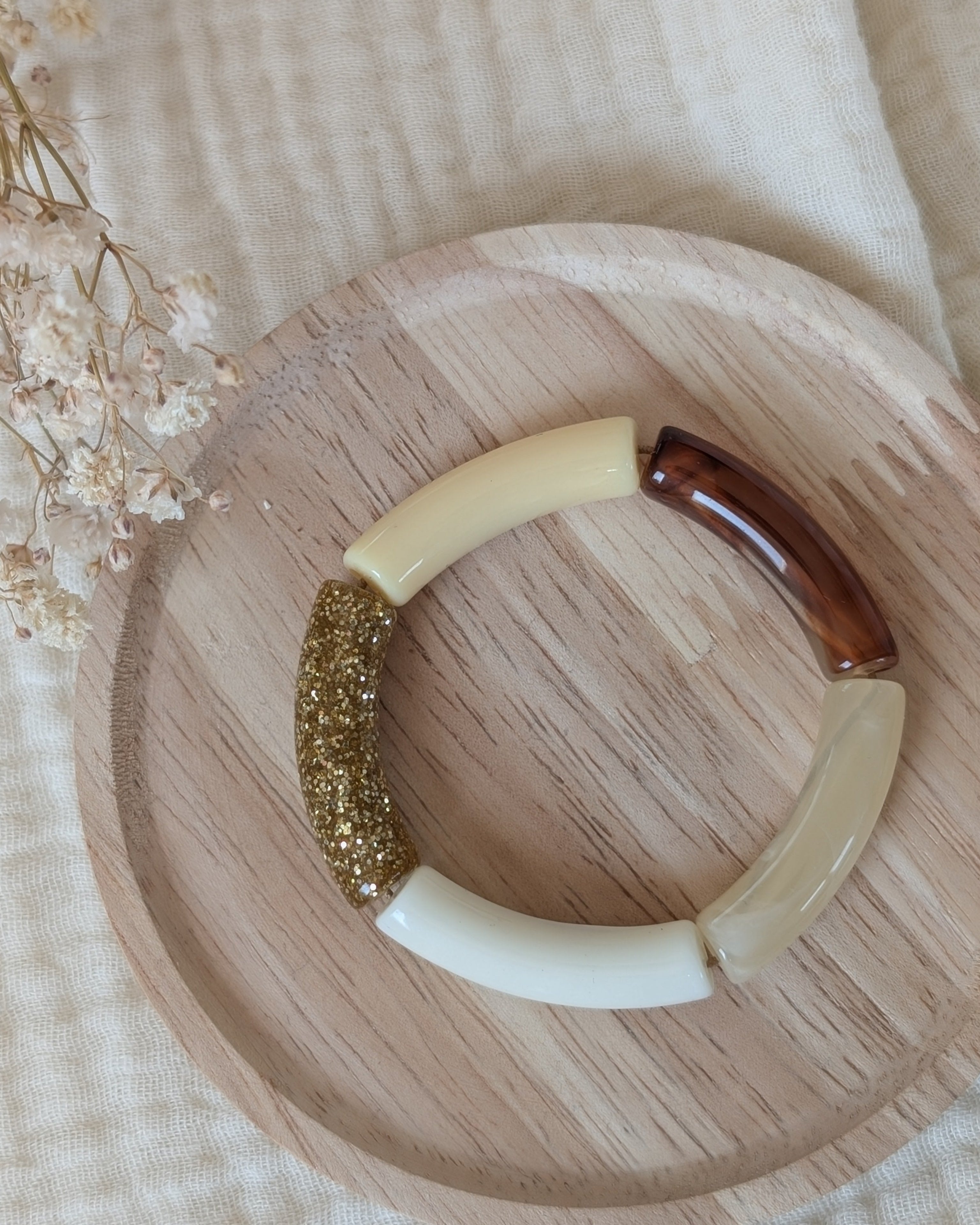 Bracelet perles tube taille enfant. Mini Lisa colori jaune pastel. Posé sur support en bois. Création La Tête dans les Nétoiles