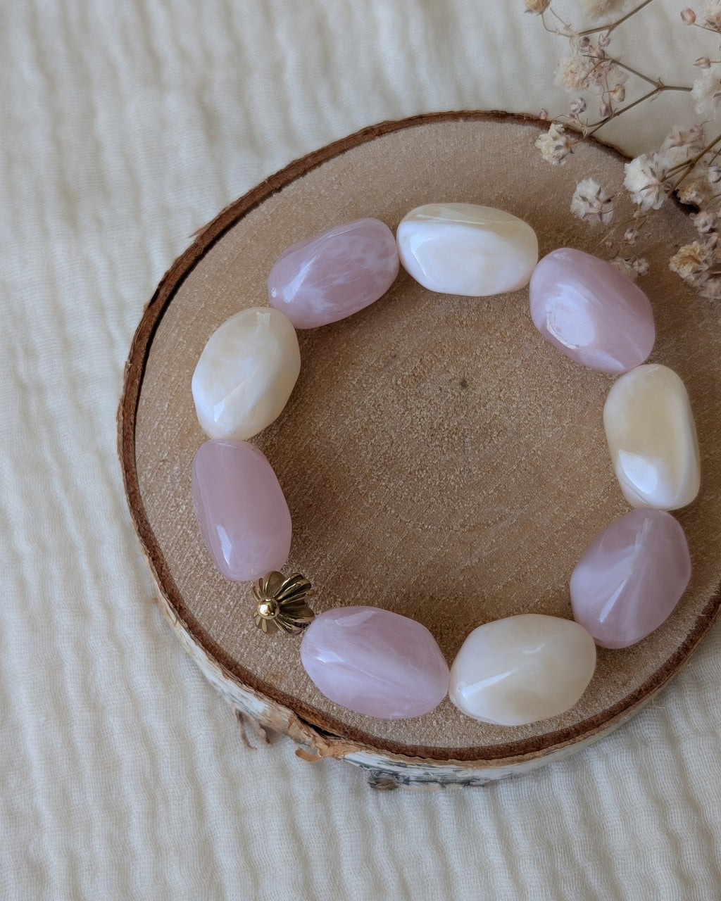 Bracelet Clea perles galets résine asymétriques rose poudré et blanc crème marbré et acier inoxydable. Posé sur un rondin. Créations artisanales La Tête dans les nétoiles