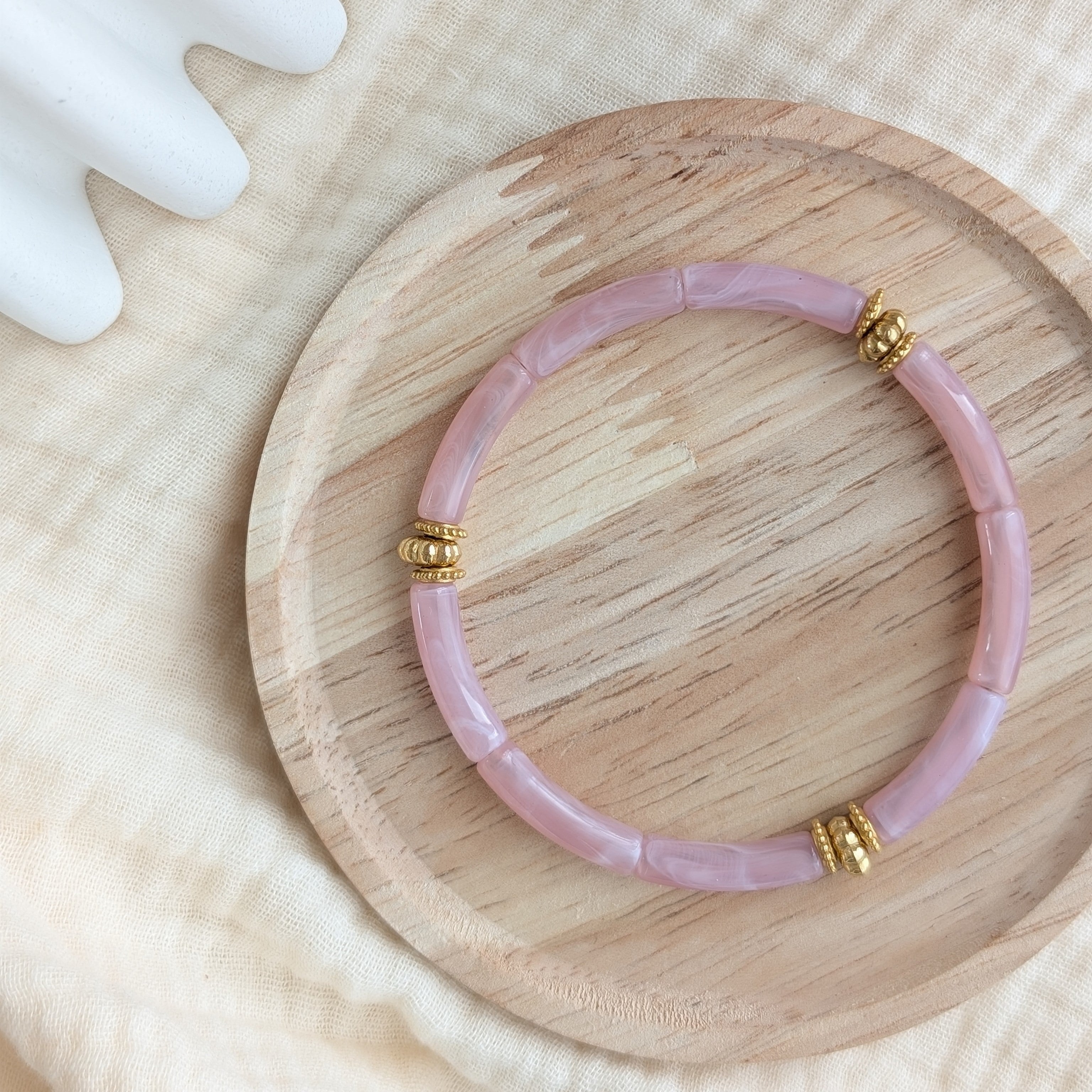Bracelet JUNE rose clair marbré sur support en bois. Perles tubes acryliques et perles dorées en acier inoxydable Création La Tête dans les Nétoiles