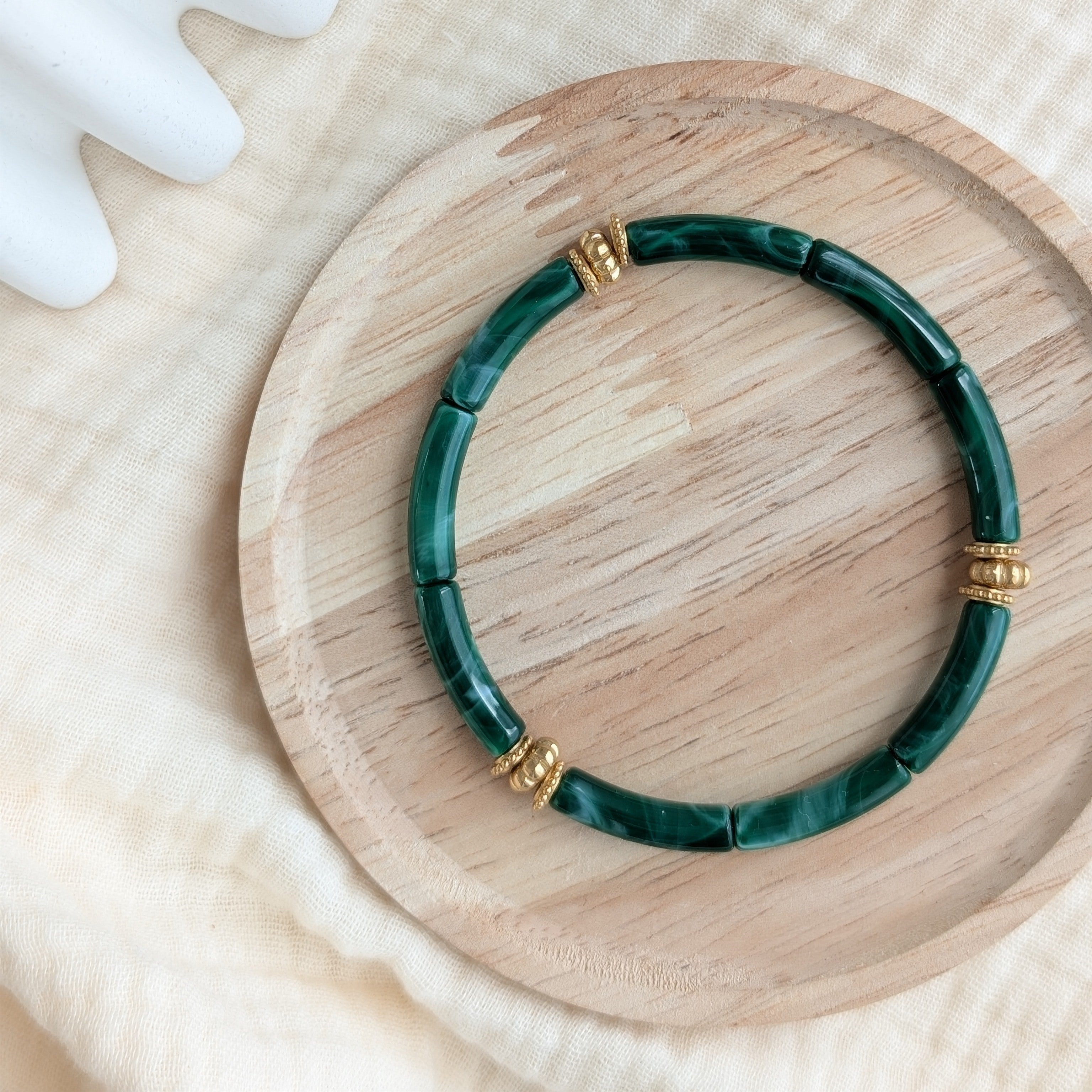 Bracelet JUNE vert émeraude marbré sur support en bois. Perles tubes acryliques et perles dorées en acier inoxydable Création La Tête dans les Nétoiles