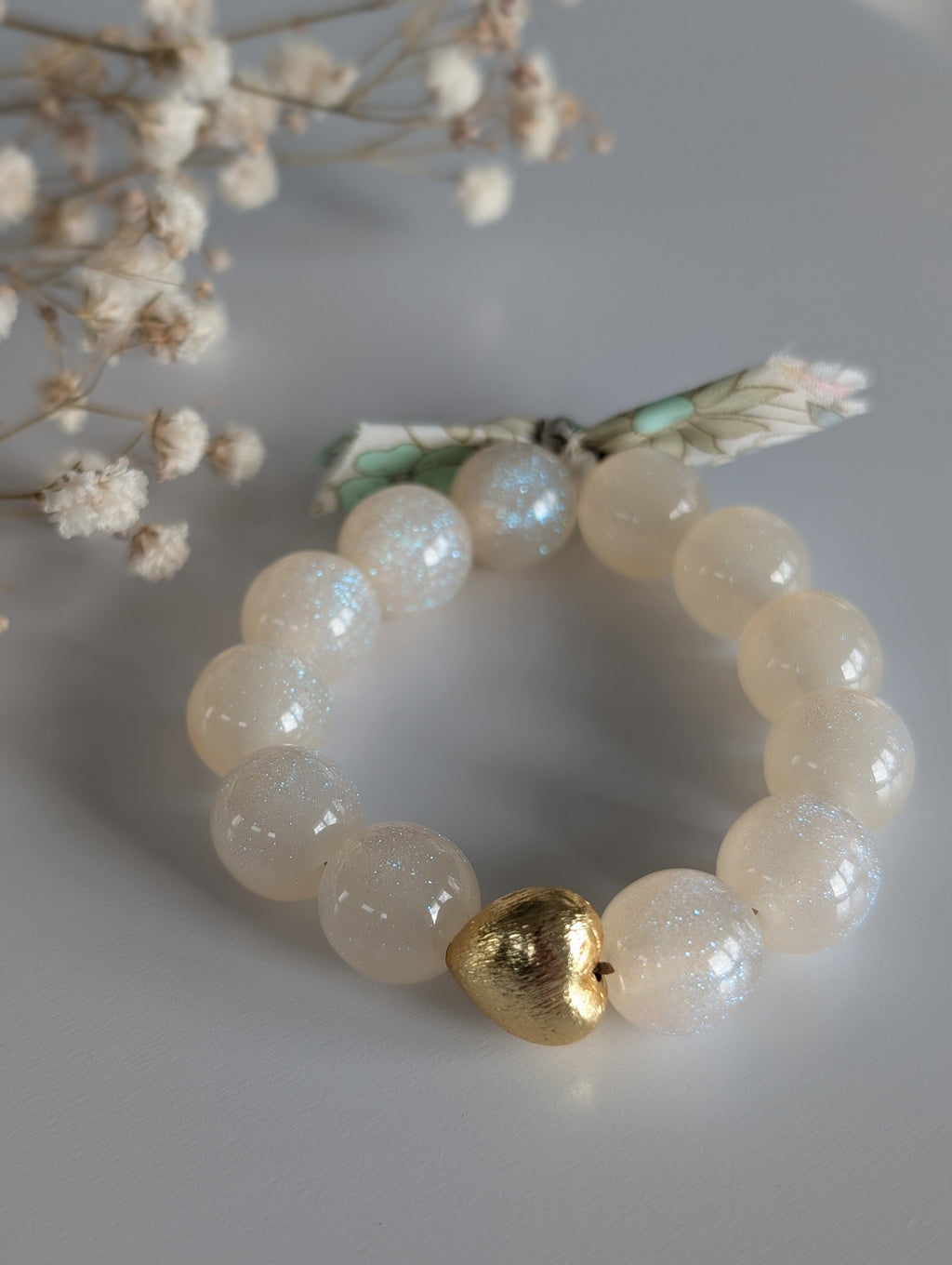 Bracelet LIBERTY GLOWY personnalisé perle coeur dorée sur fond blanc. Perle à paillettes blanc irisé. Bracelet à message mère fille. Ruban liberty. Création la Tête dans les Nétoiles