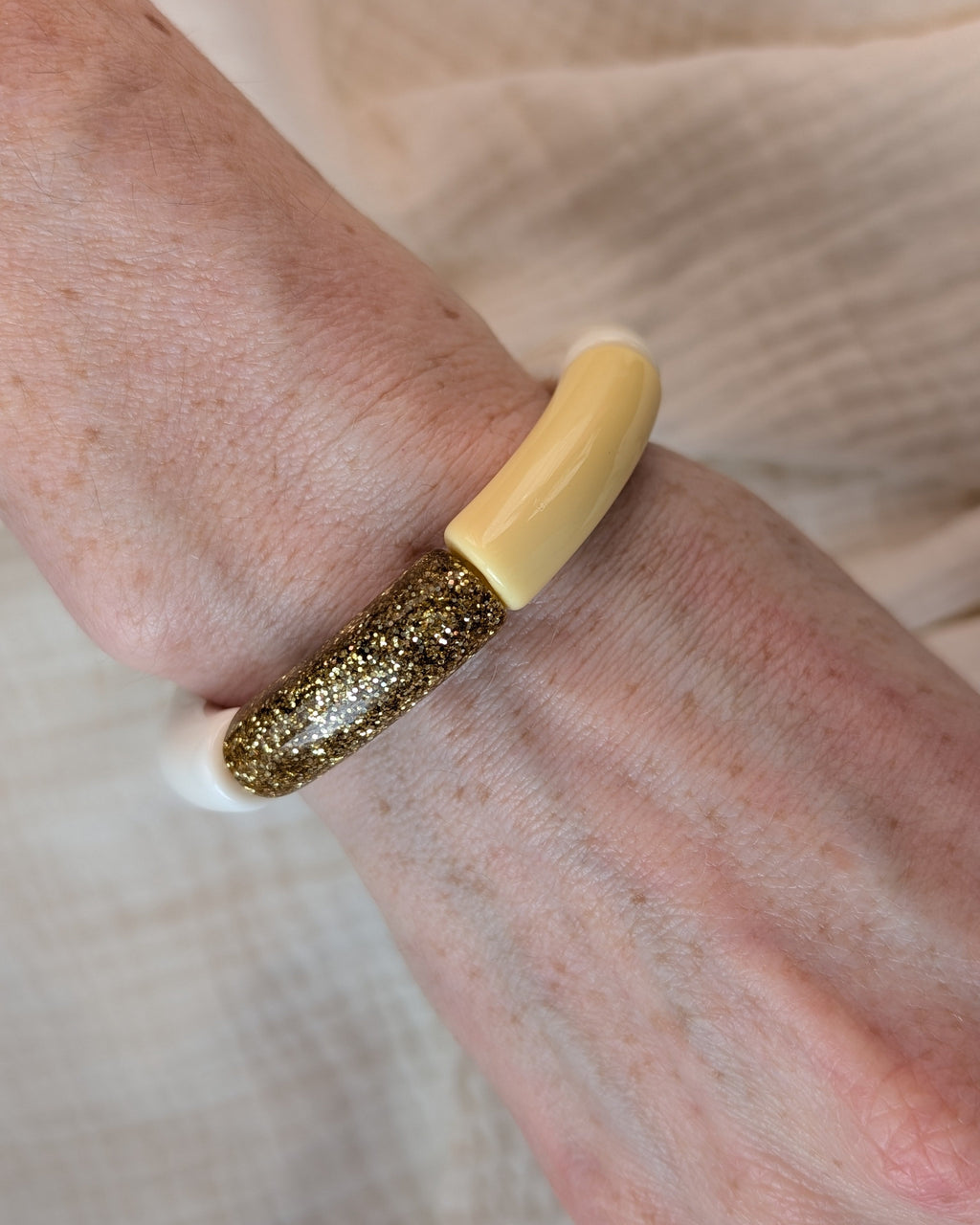 Bracelet perles tube MONA jaune pastel et glitter doré. Porté sur poignet de femme. Création LA Tête dans les Nétoiles