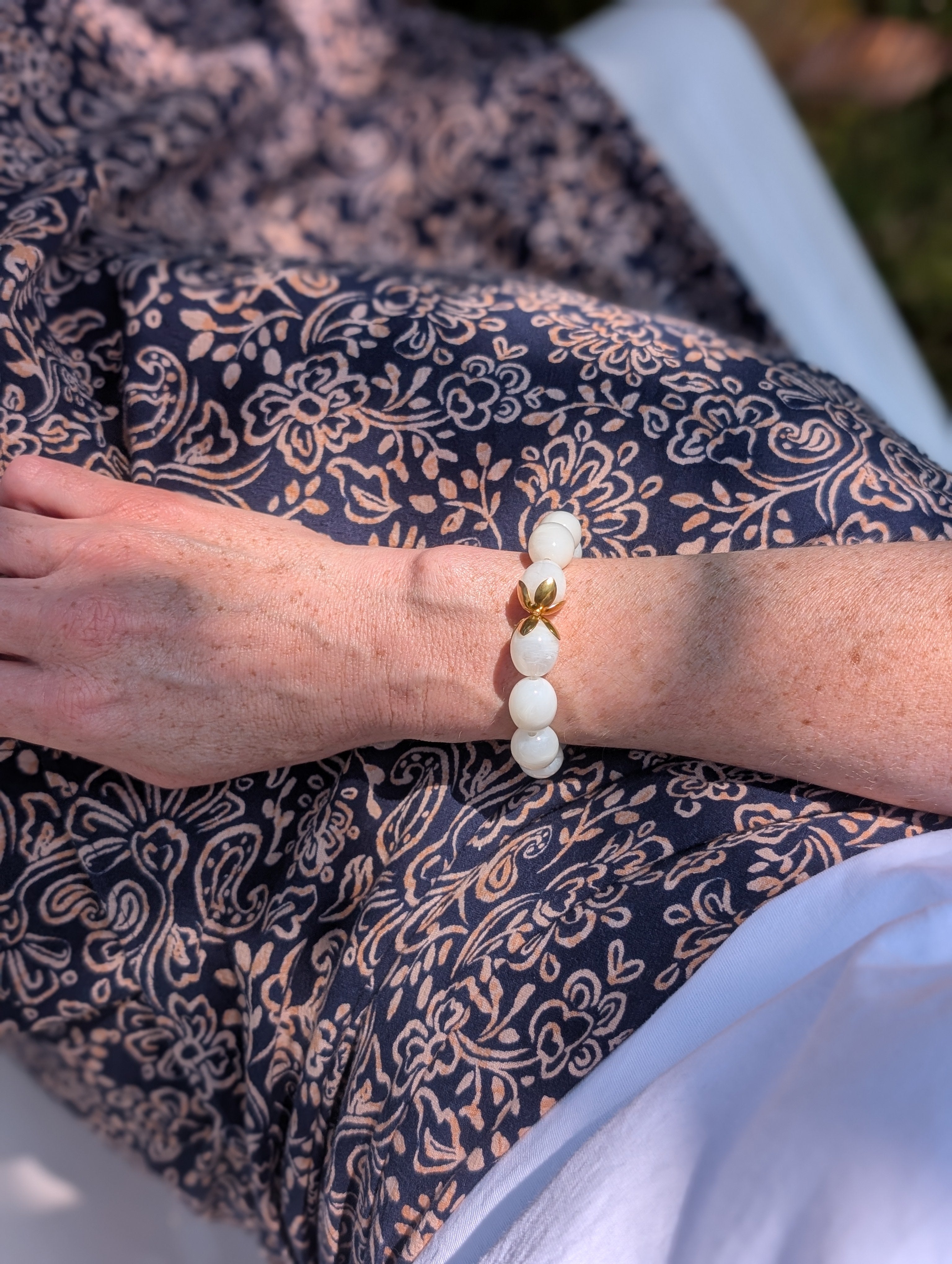 Bracelet Olivia porté par une femme avec poignet de 15.5 cm et une jupe fleurie bleue. Créations artisanales La Tête dans les Nétoiles