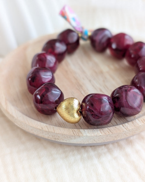 Bracelet Perles résine Adèle couleur grenat marbré pris en gros plan perle coeur doré brossé plaqué or en gros plan. Création fait main La Tête dans les Nétoiles