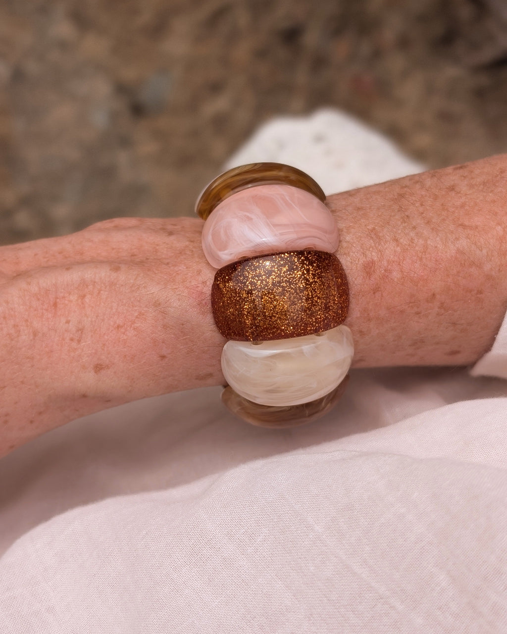 Bracelet Ysée Rose miel écru glitter cuivré porté par une femme avec une blouse blanche . Création artisanale La Tête dans les Nétoiles 