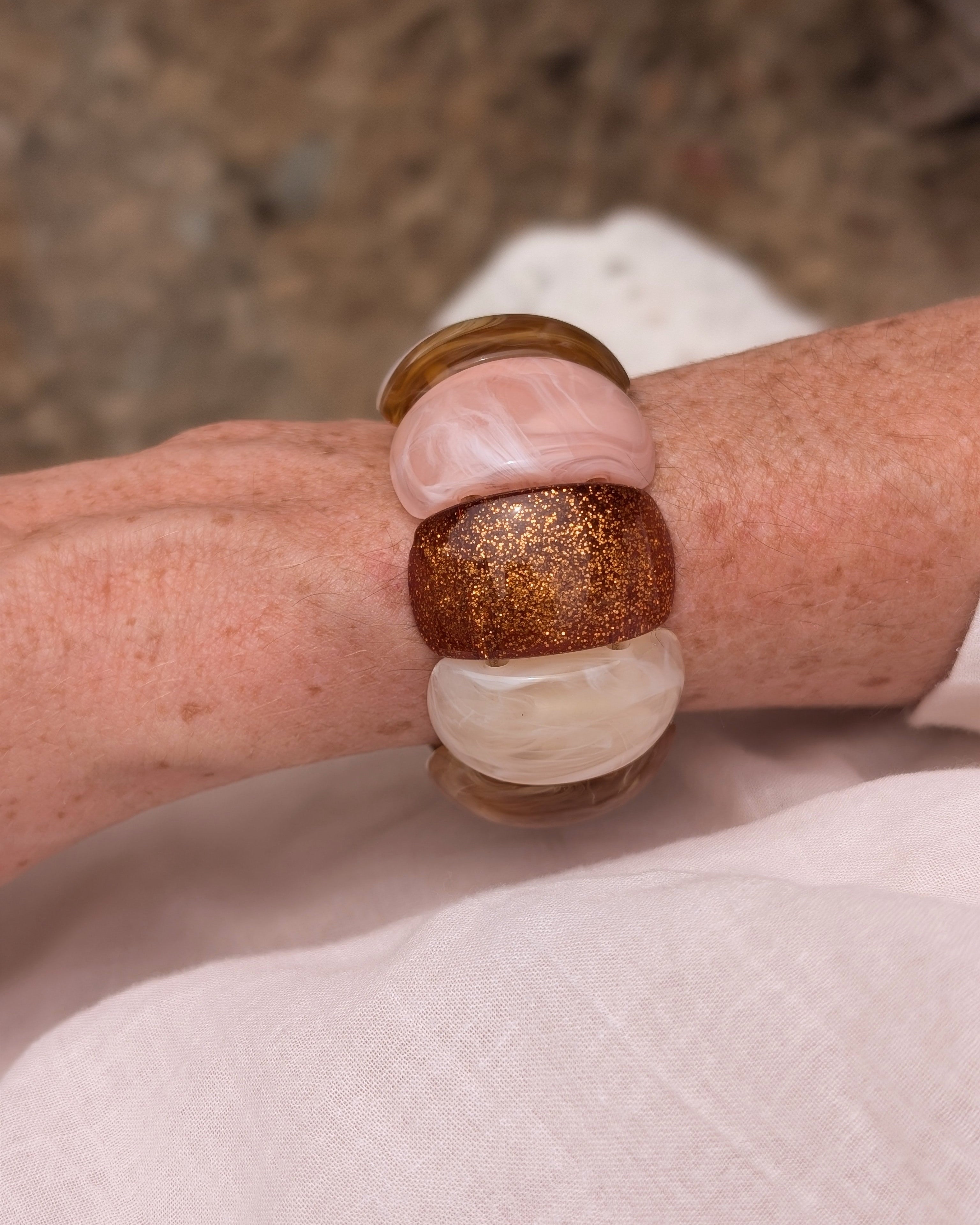 Bracelet Ysée Rose miel écru glitter cuivré porté par une femme avec une blouse blanche . Création artisanale La Tête dans les Nétoiles 