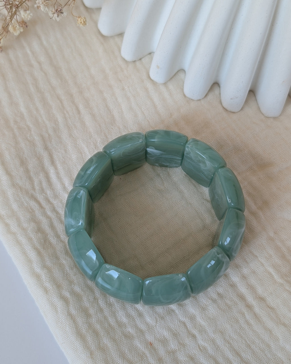 Bracelet Ysee vert sauge plan sur le dessus. Perles acryliques domes. Posé sur gaze de coton. Créations La Tête dans les Nétoiles