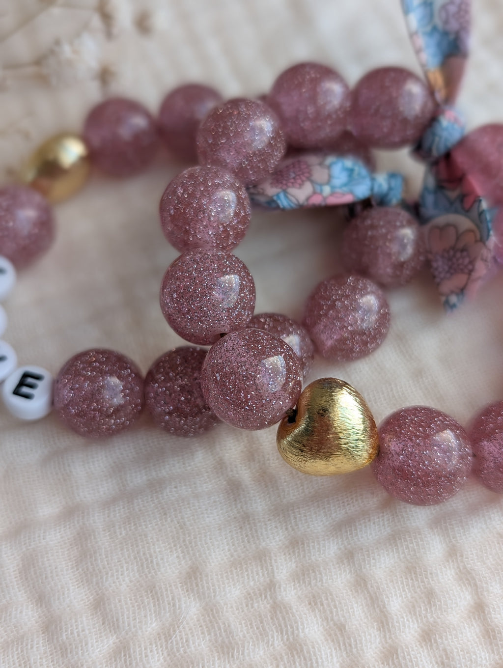 Bracelets en gros plan rose paillettes et perle coeur en plaqué or. Bracelet personnalisé mots doux mère fille . Créations La Tête dans les Nétoiles