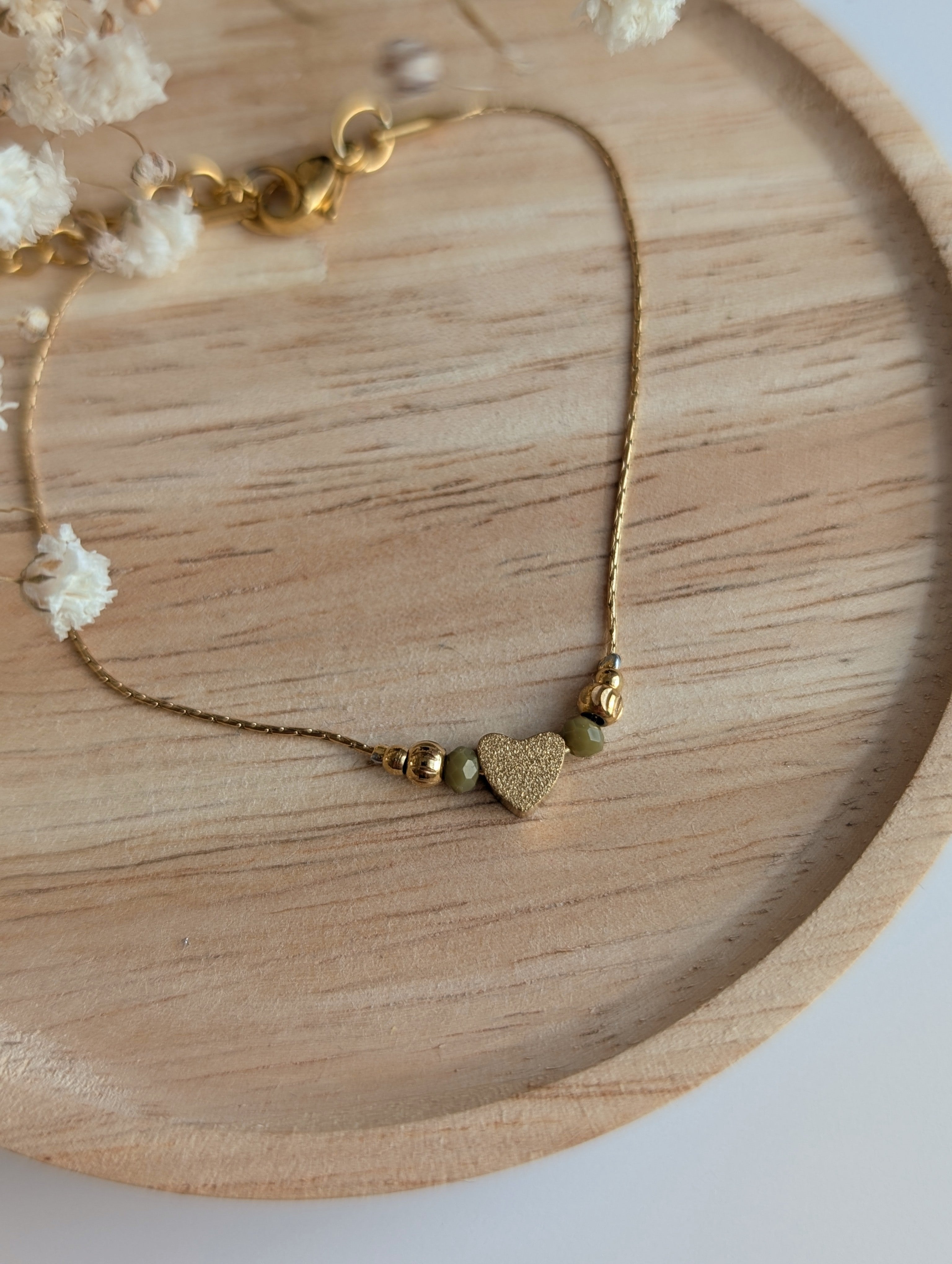 Bracelet fin chaine maille serpentine en acier inoxydable doré et perle coeur diamanté et  en verre vert olive. Créations la Tête dans les Nétoiles