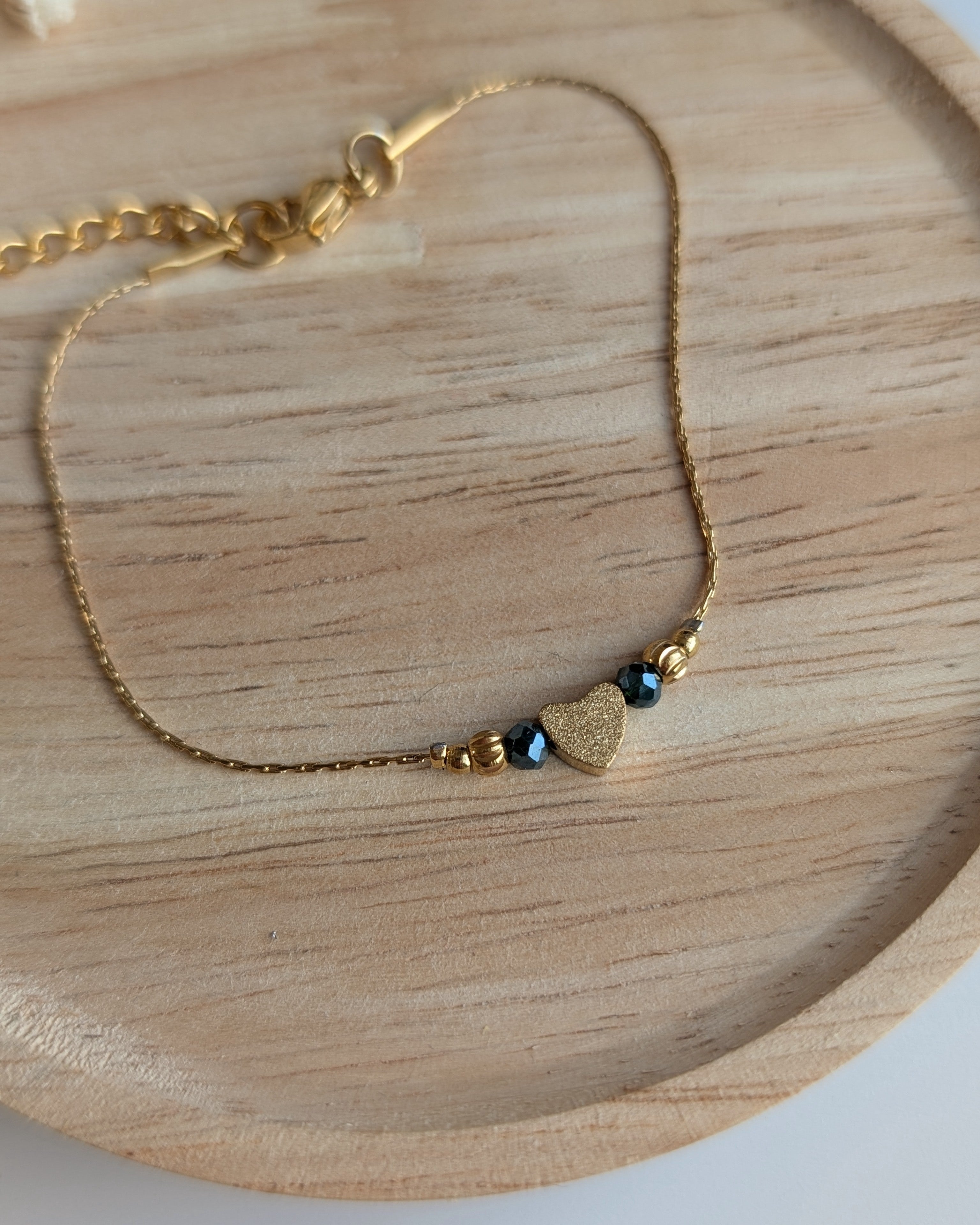 Bracelet fin minimaliste en chaîne maille serpentine en acier inoxydable doré et perle coeur diamanté et  en verre gris irisé. Créations la Tête dans les Nétoiles