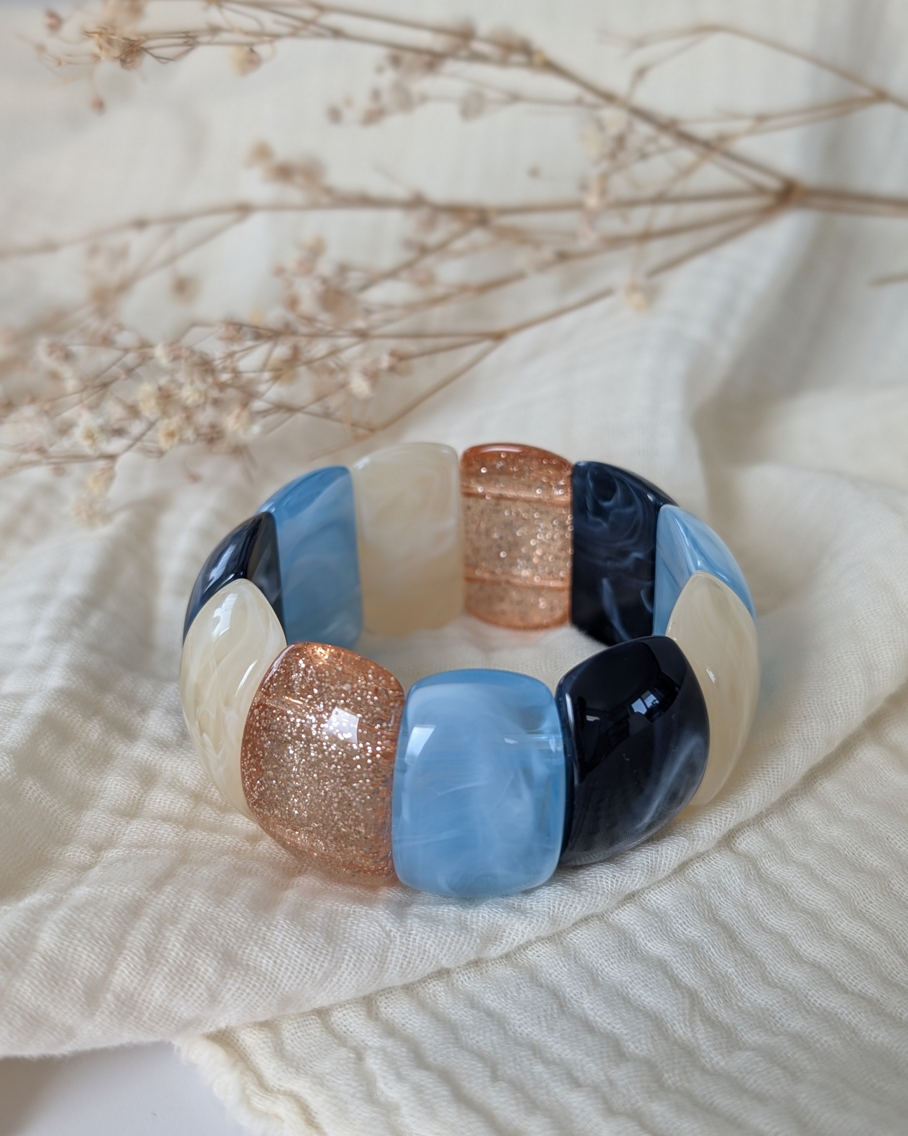 Bracelet manchette élastique Ysée bleu marine et bleu ciel et glitter champagne doré. Posé sur gaze de coton. Création artisanale la Tête dans les Nétoiles 
