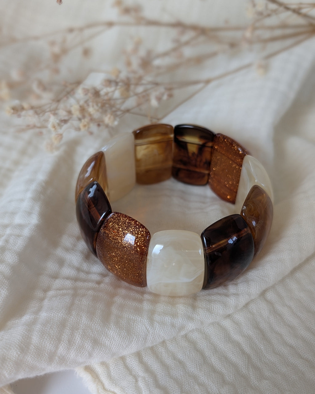 Bracelet manchette élastique Ysée miel caramel écru glitter cuivré vue de dessus. Posé sur la gaze de coton. Création artisanale la Tête dans les Nétoiles 