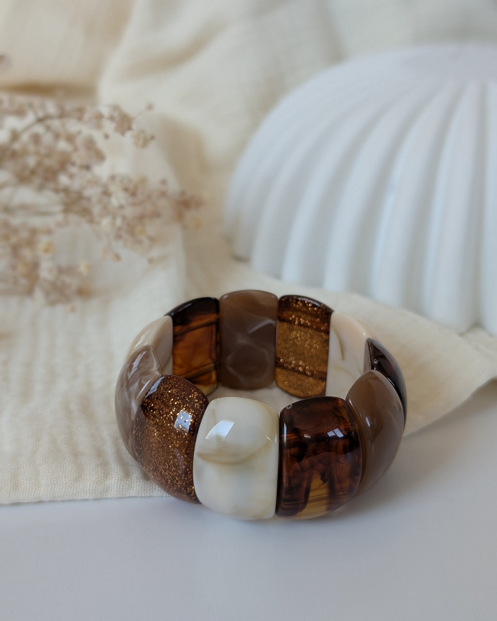 Bracelet manchette Ysée nuance de marron glitter posé sur gaze de coton. Création La Tête dans les Nétoiles