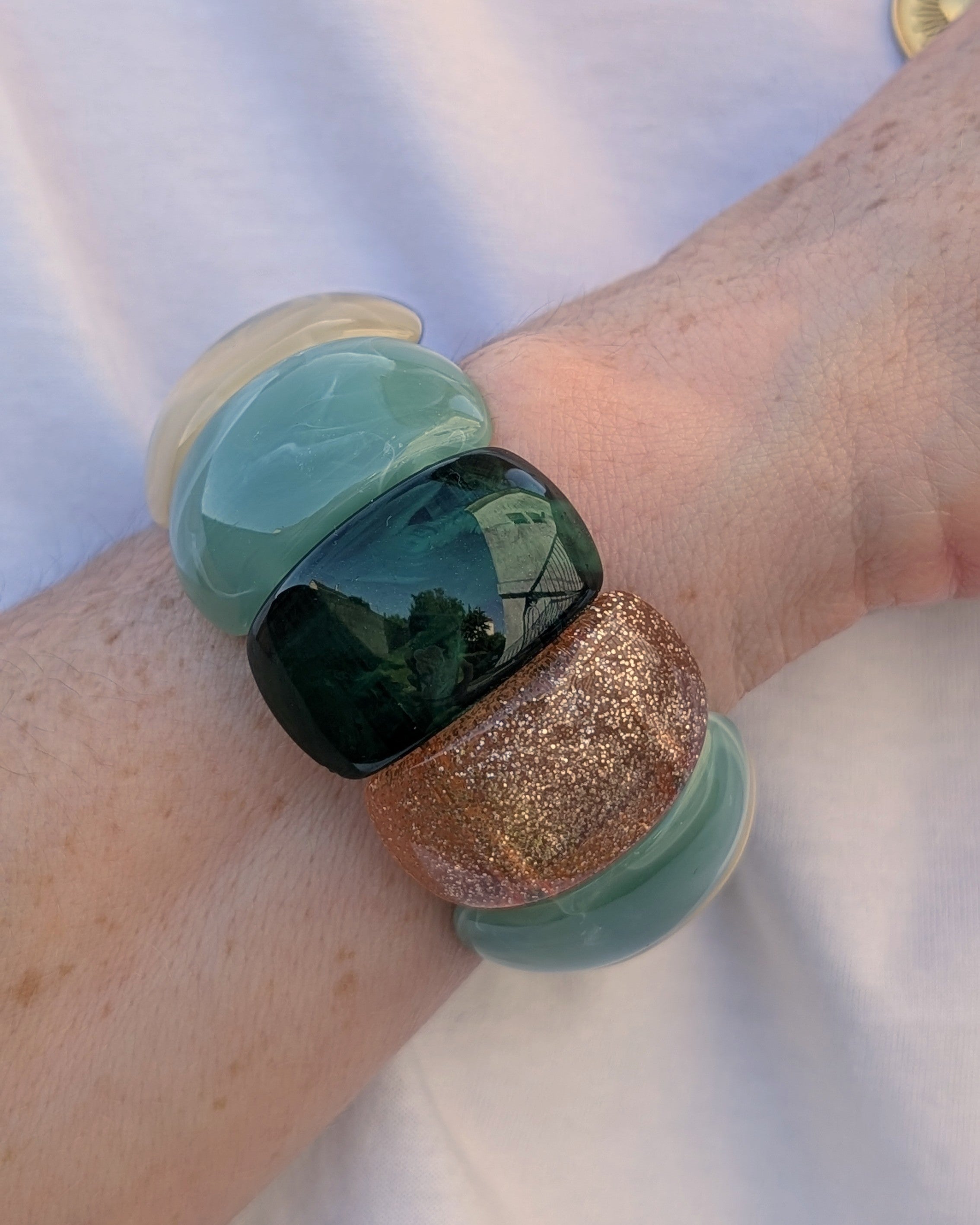 Bracelet manchette Ysée perles vert sauge et vert marbré porté par une femme. Création artisanale la Tête dans les Nétoiles 