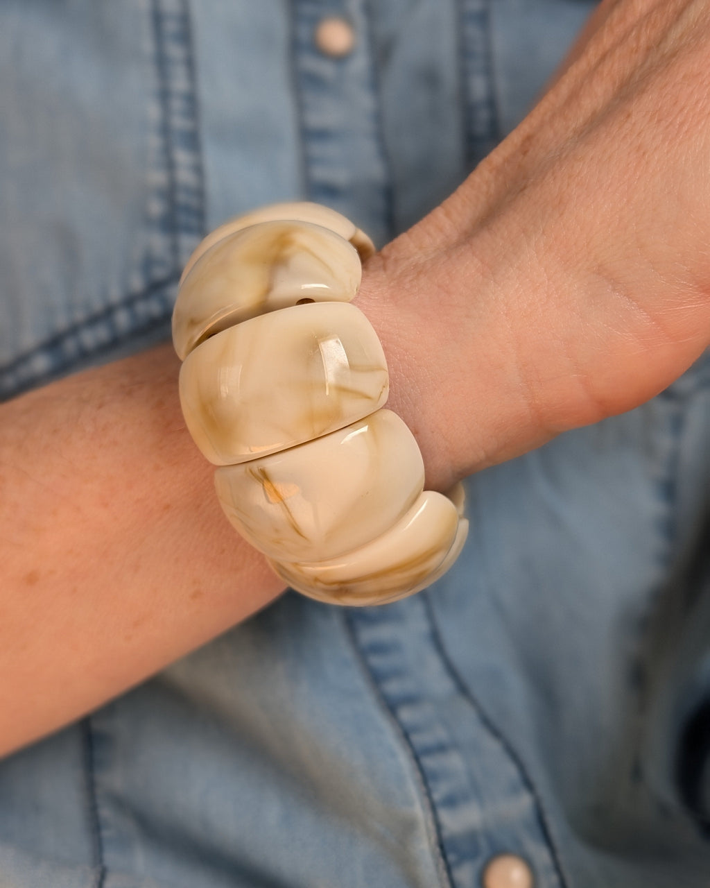 Bracelet manchette Ysée colori nougat marbré . Porté par une femme avec chemise en jean. création la Tête dans les Nétoiles