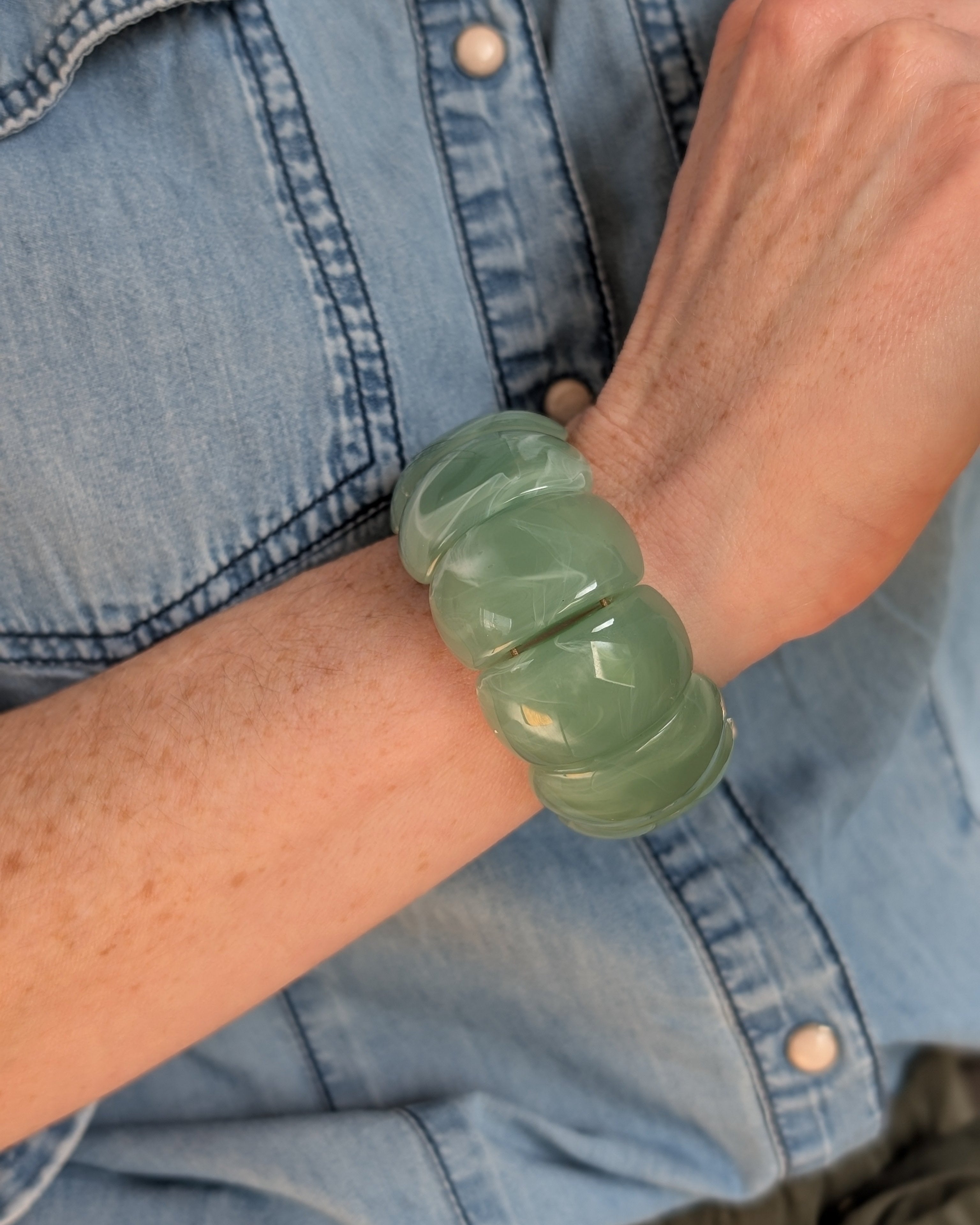 Bracelet manchette Ysée vert sauge porté au poignet d'une femme. Création La Tête dans les Nétoiles