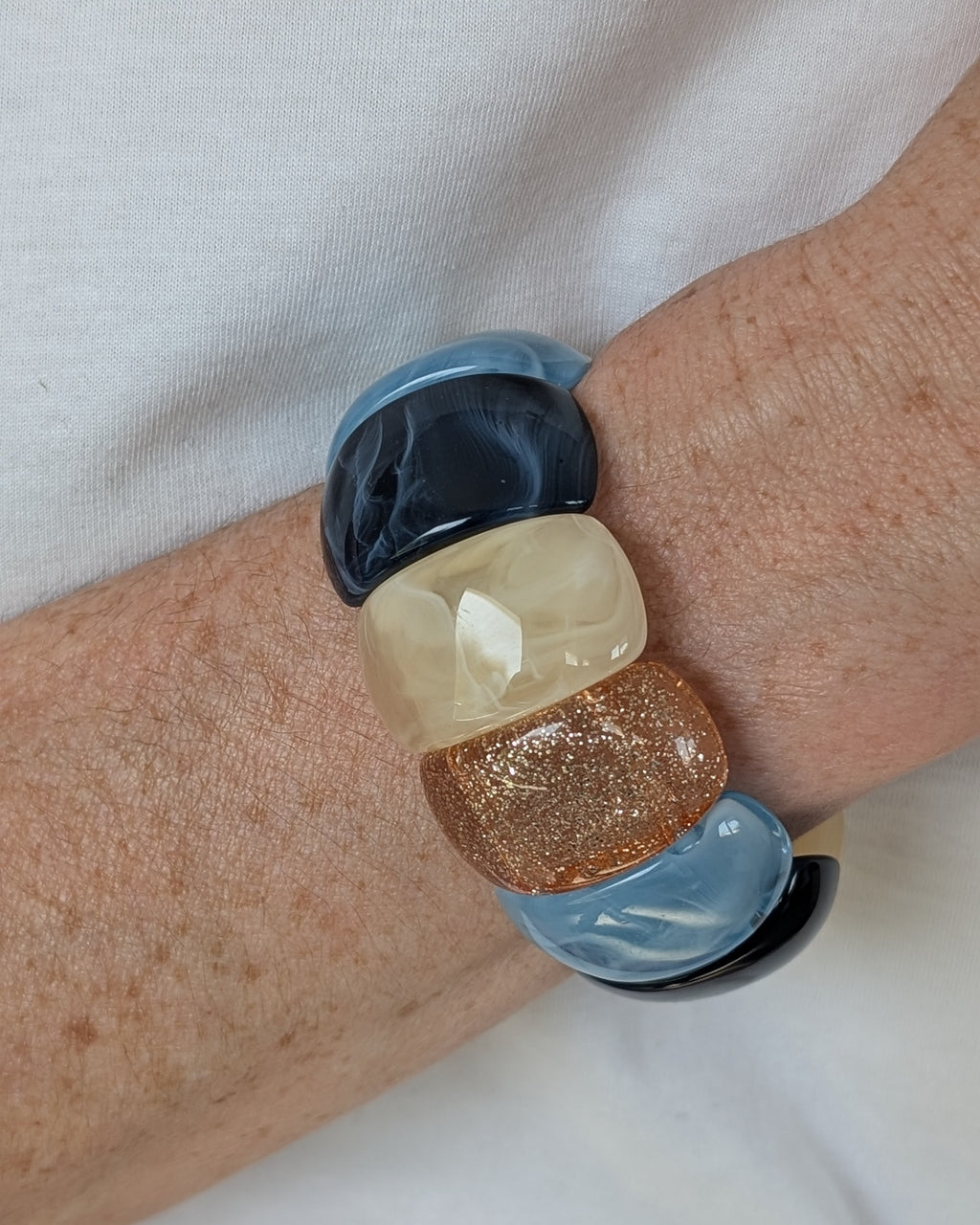 Bracelet manchette élastique Ysée bleu écru glitter champagne doré porté au poignet d'une femme. Création artisanale la Tête dans les Nétoiles 