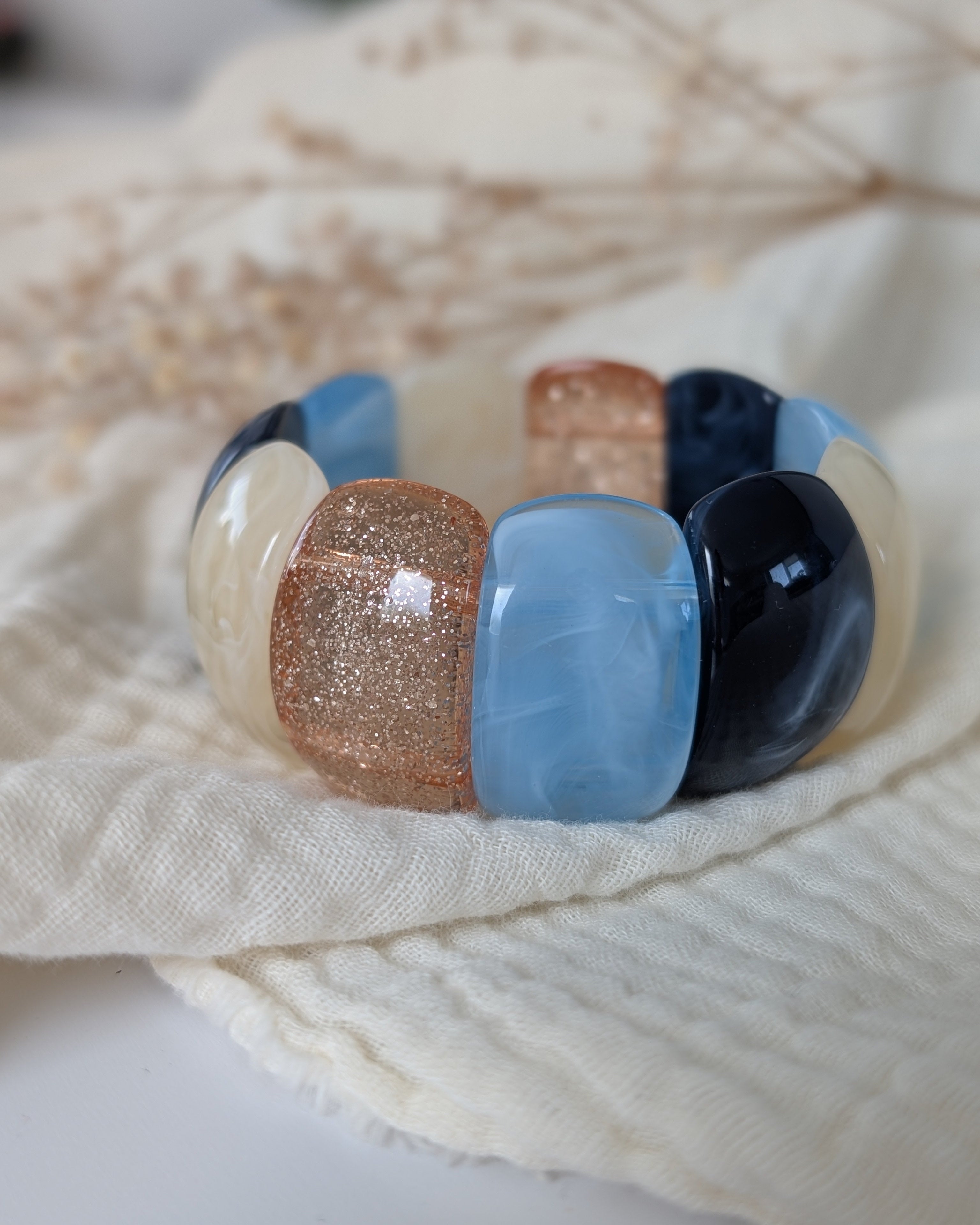 Bracelet manchette élastique Ysée bleu posé sur gaze de coton. Création artisanale la Tête dans les Nétoiles 