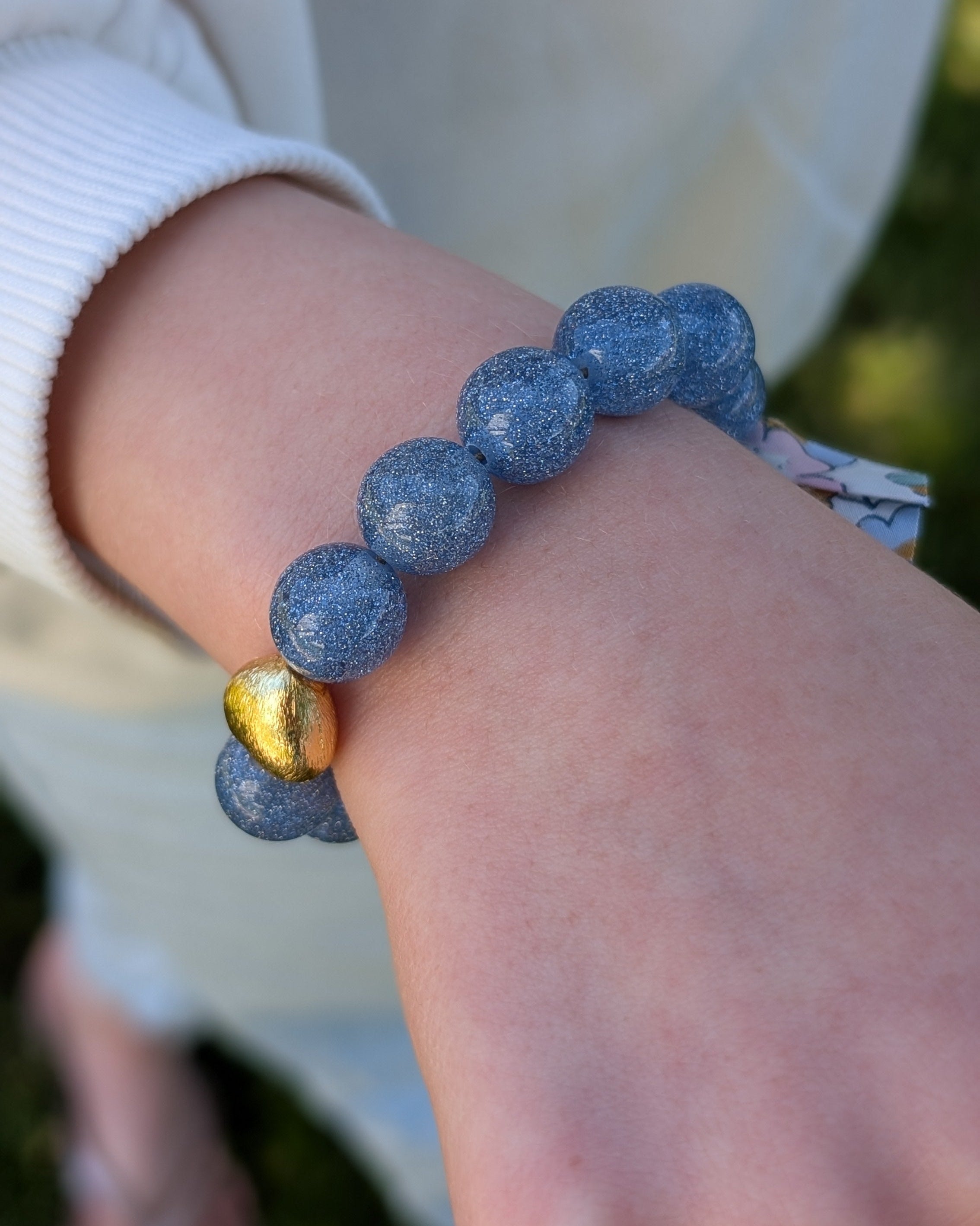 Bracelet à paillettes bleu clair porté par une petite fille. Personnalisable Création La Tête dans les Nétoiles