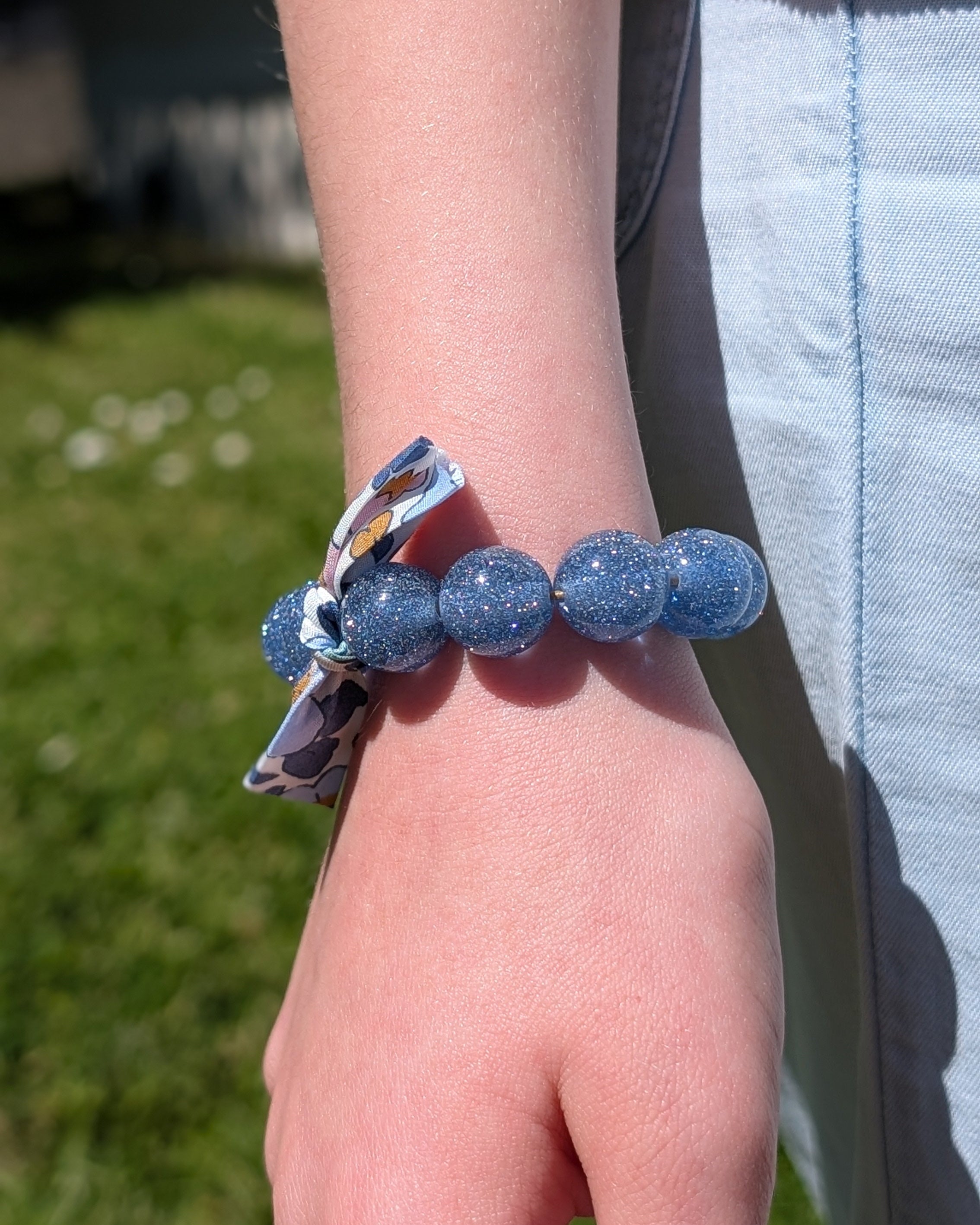 Bracelet perles paillettes bleu clair et ruban liberty porté au poignet d'une petit fille. Création La Tête dans les Nétoiles