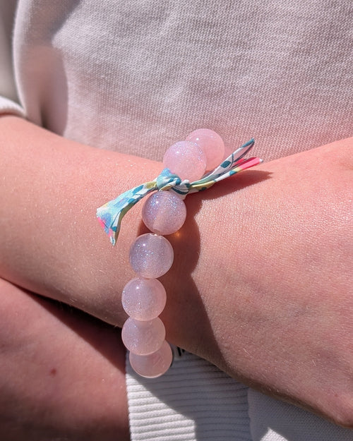 Bracelet perle à paillettes rose clair orné d'un ruban liberty porté par une petite fille. Créations fait main La Tête dans les Nétoiles