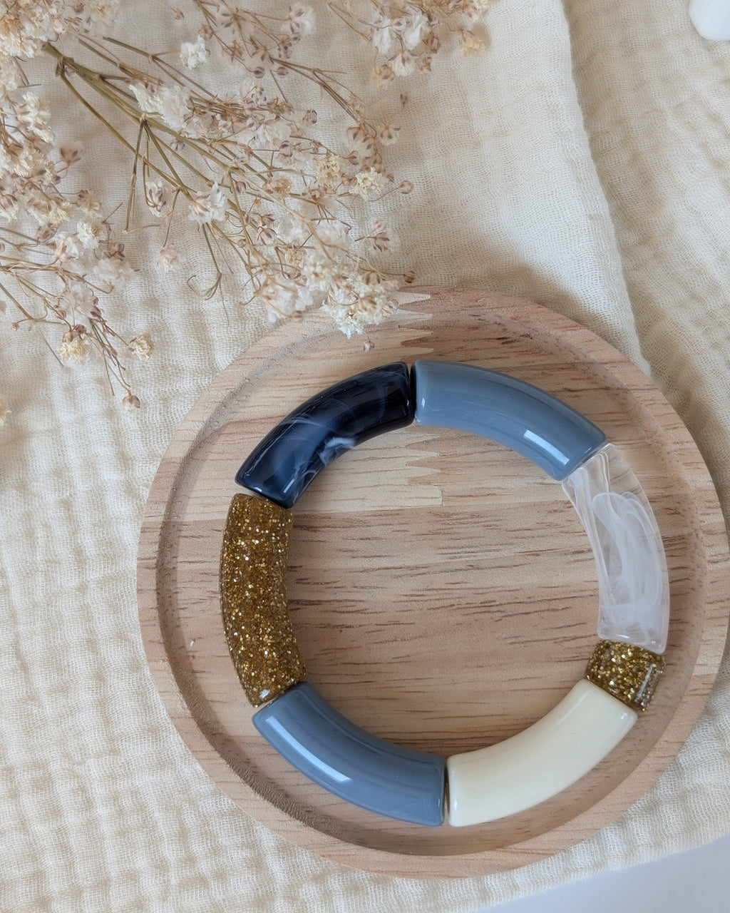 Bracelet perle tube MONA en bleu et perle tranparente posé sur support en bois. Création La Tête dans les Nétoiles
