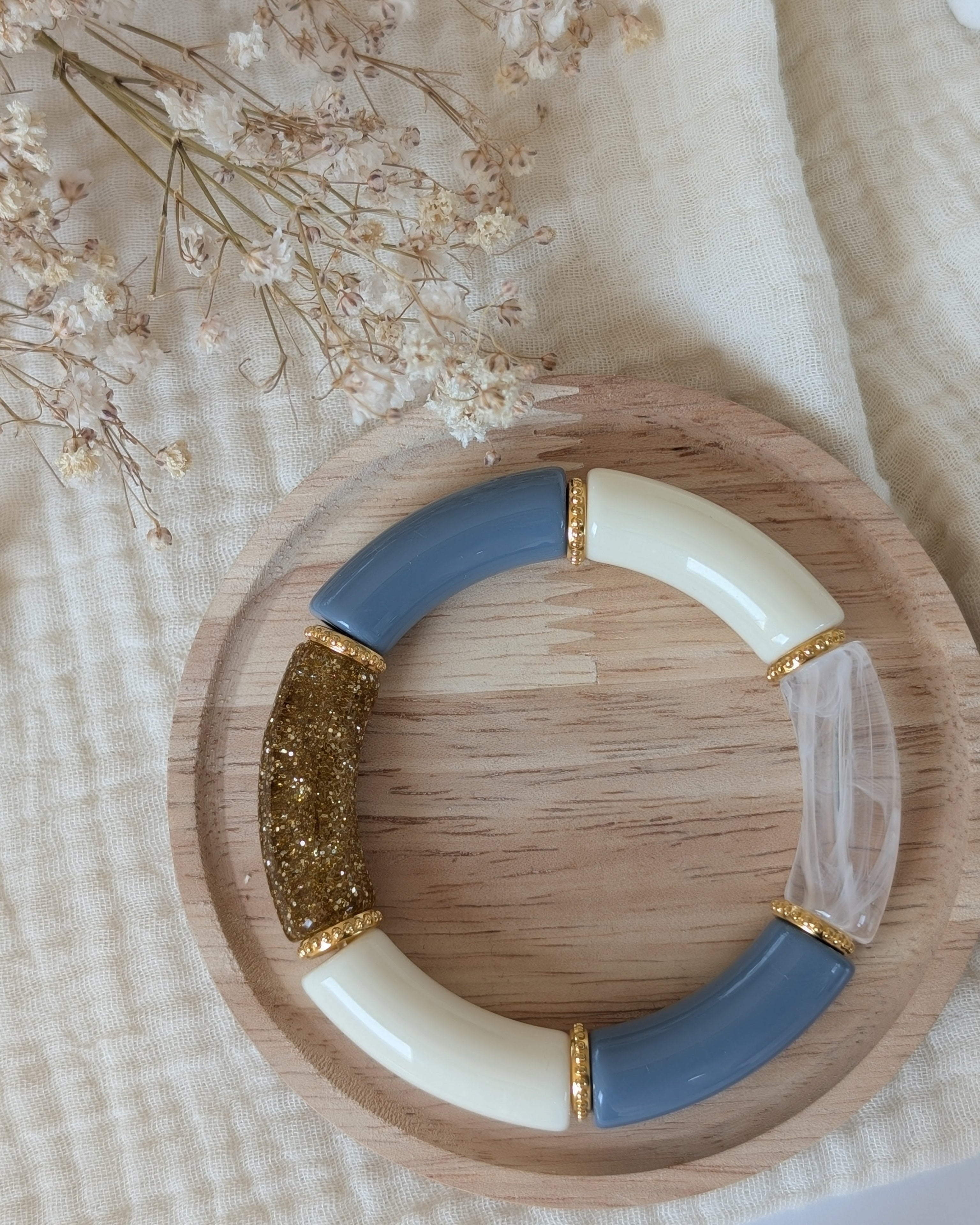 Bracelet perles tube Marie bleu blans transparent et glitter doré avec perles intercalaires dorées haute qualité. Sur support en bois. Création La Tête dans les nétoiles