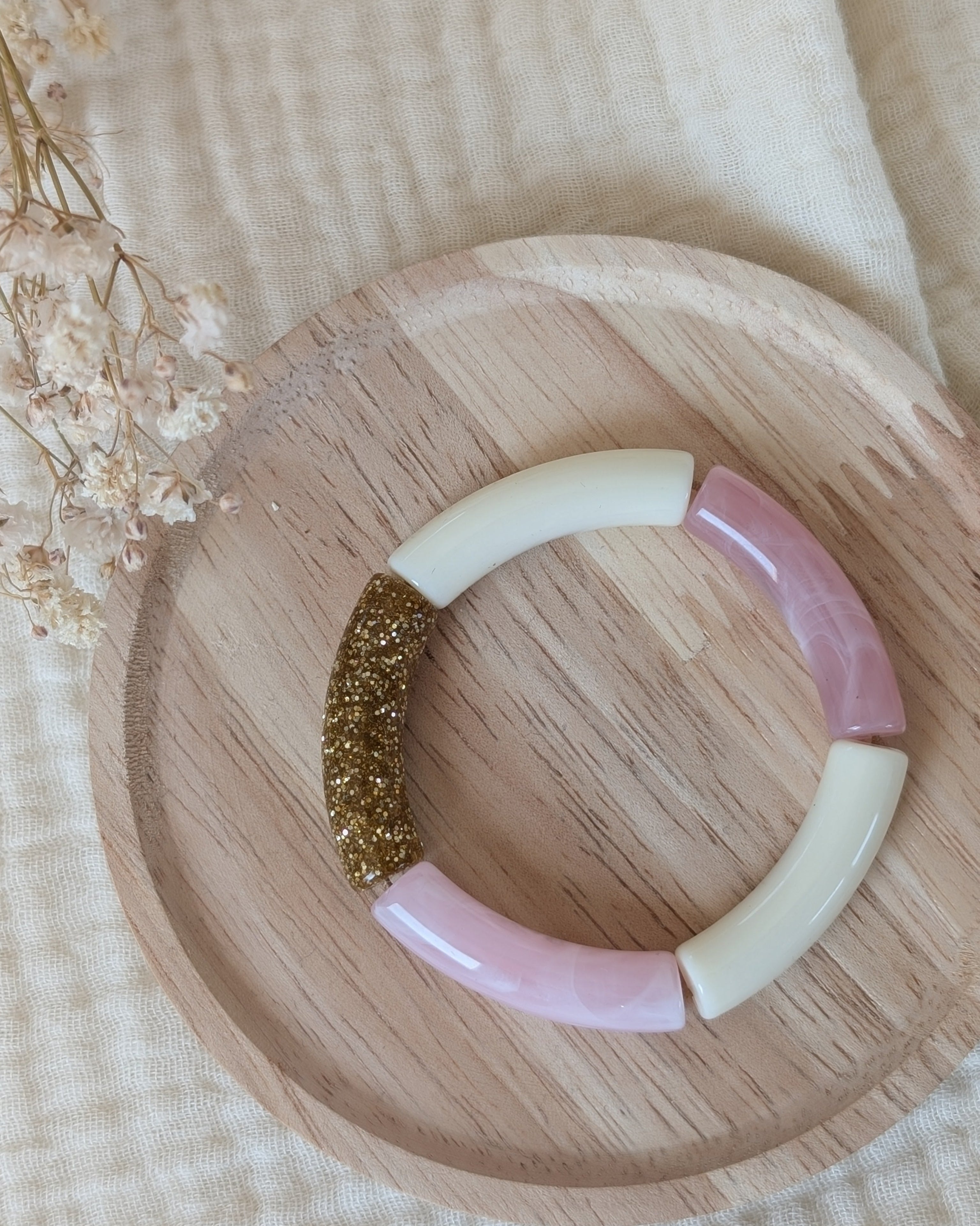 Bracelet perles tube rose tendre taille enfant posé sur support en bois. Création La Tête dans les nétoiles