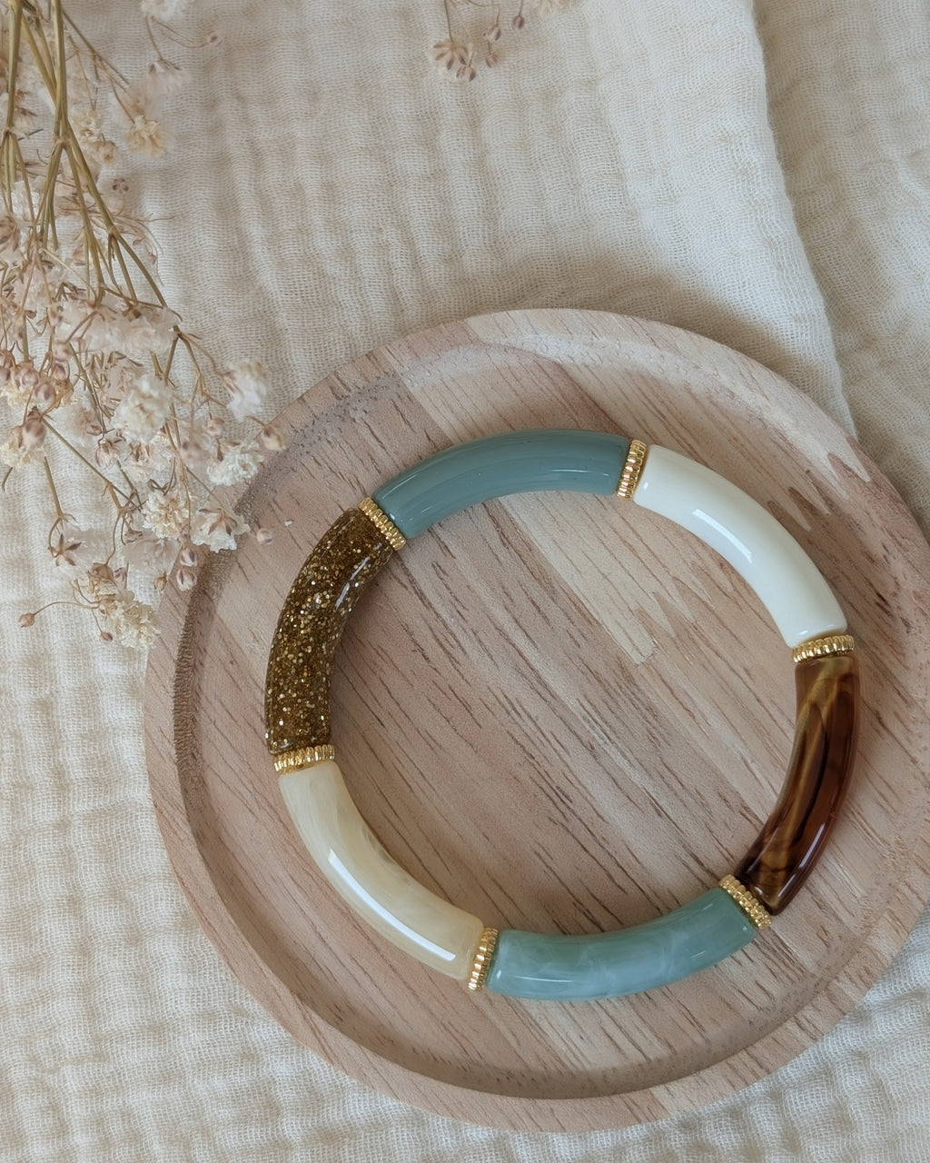 bracelet lison perle tube vert sauge pastel et glitter doré. Avec intercalaire doré. posé sur plateau en bois. Création La Tête dans les Nétoiles