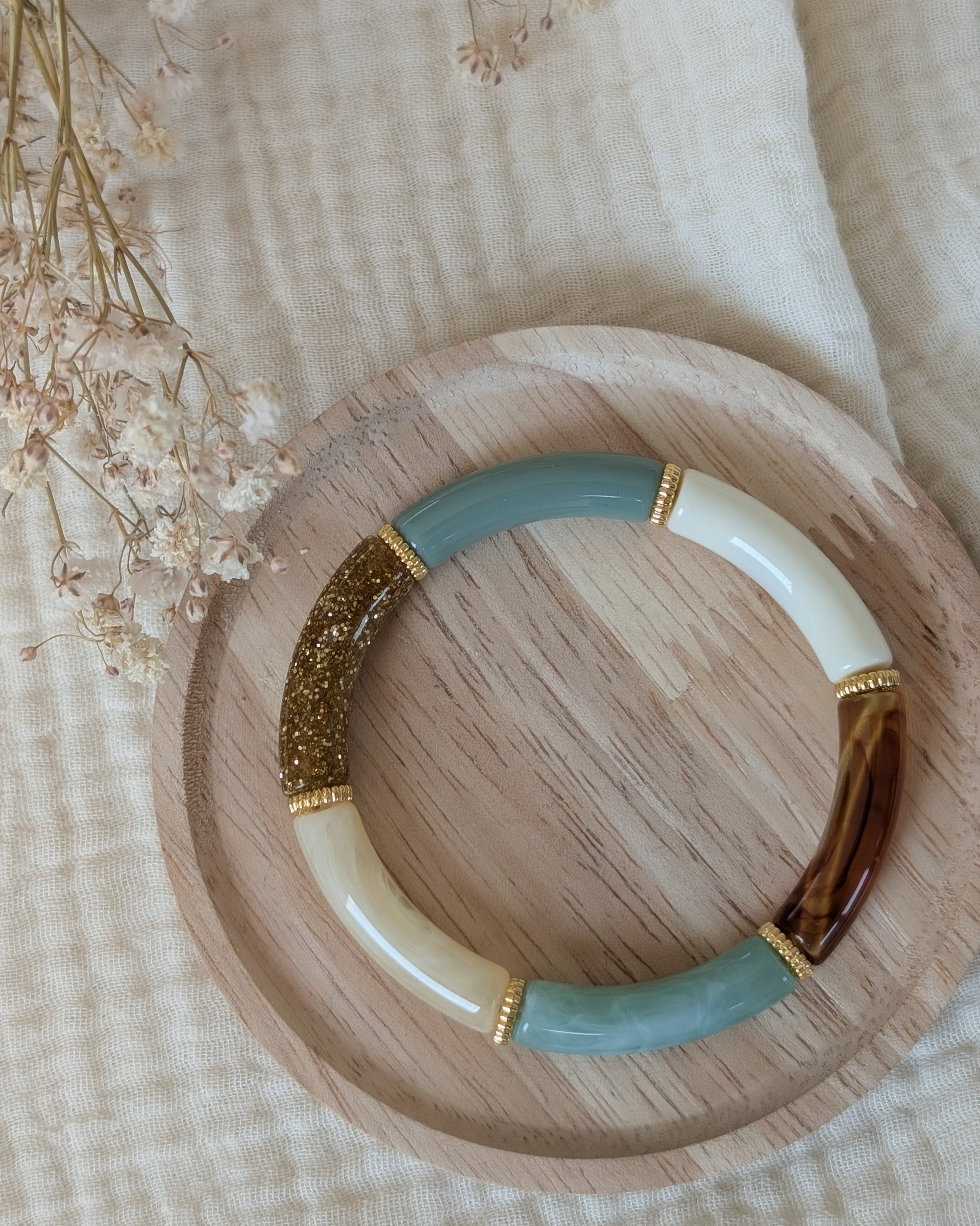 bracelet lison perle tube vert sauge pastel et glitter doré. Avec intercalaire doré. posé sur plateau en bois. Création La Tête dans les Nétoiles