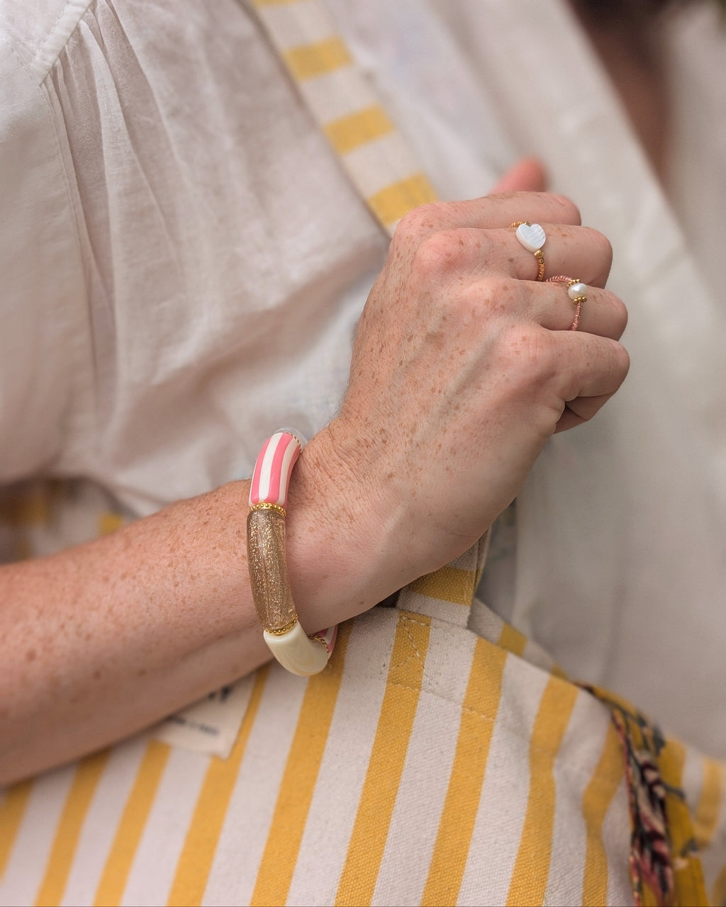 bracelet perles tube à rayures rose porté par une femme. Créations artisanales La Tête dans les Nétoiles
