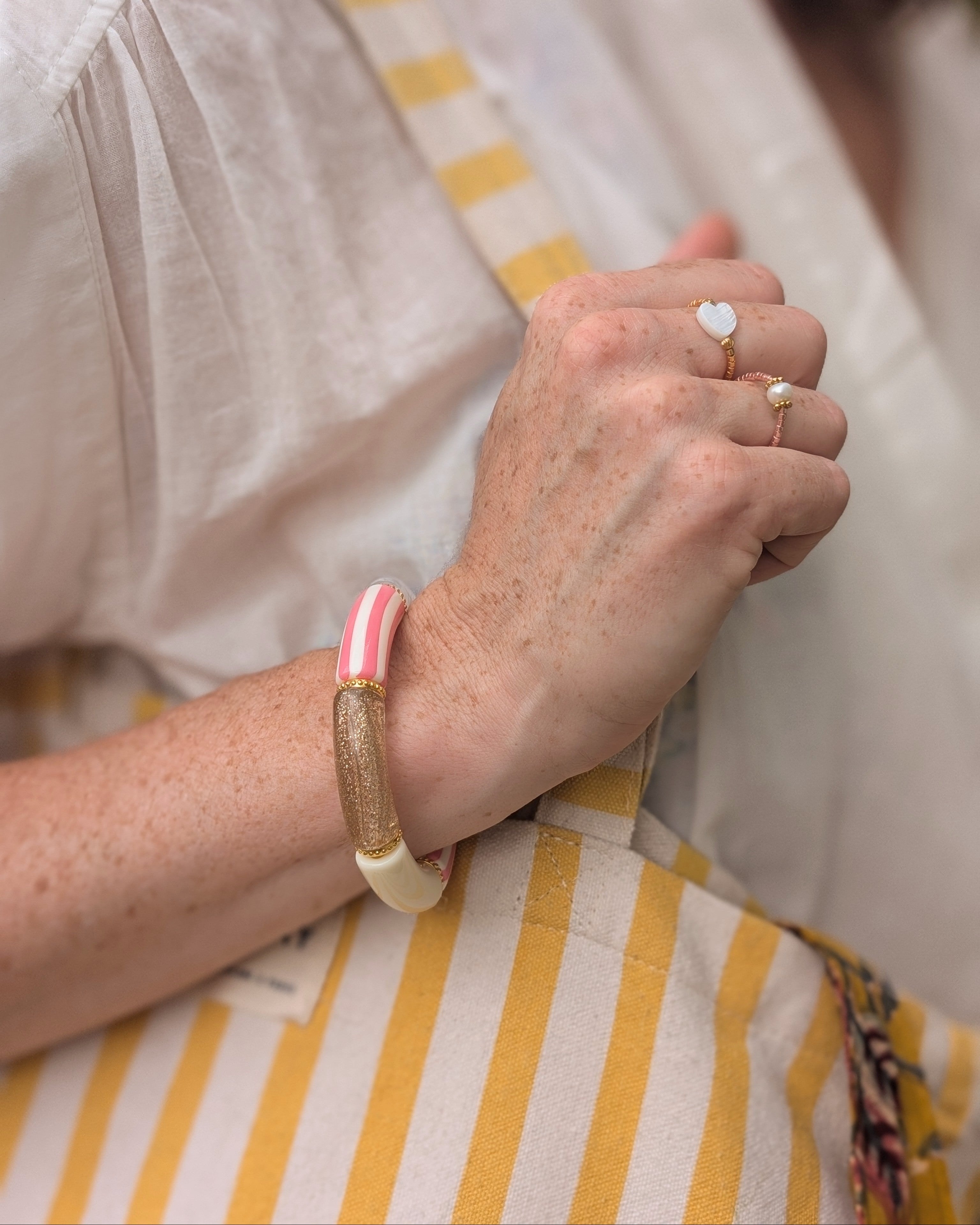 bracelet perles tube à rayures rose porté par une femme. Créations artisanales La Tête dans les Nétoiles