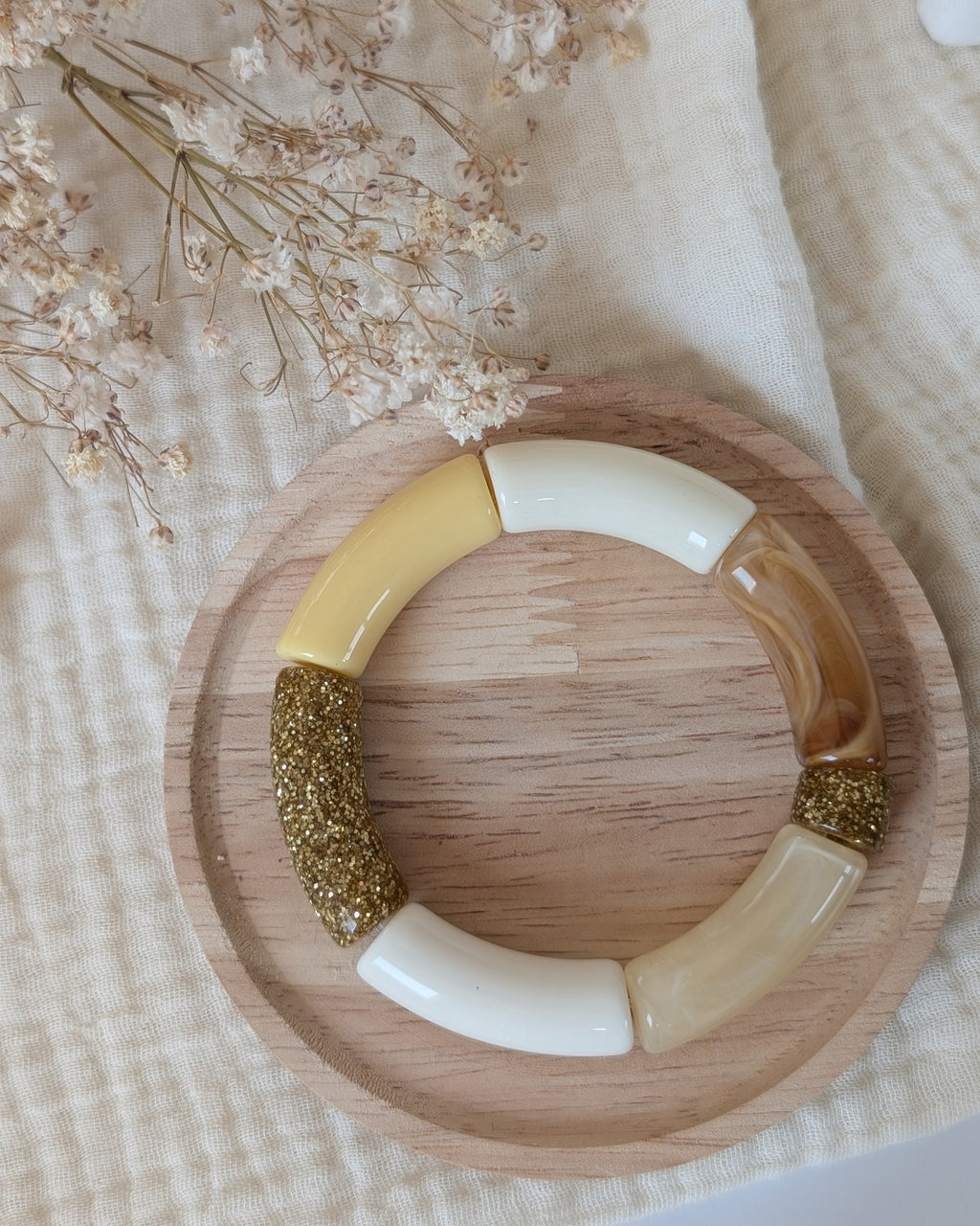 Bracelet Mona perles tubes jaune pastel et glitter doré. posé sr support en bois. Création la tête dans les nétoiles